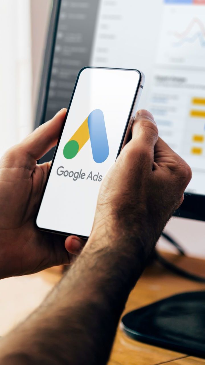 A person is holding a cell phone with the google ads logo on it.