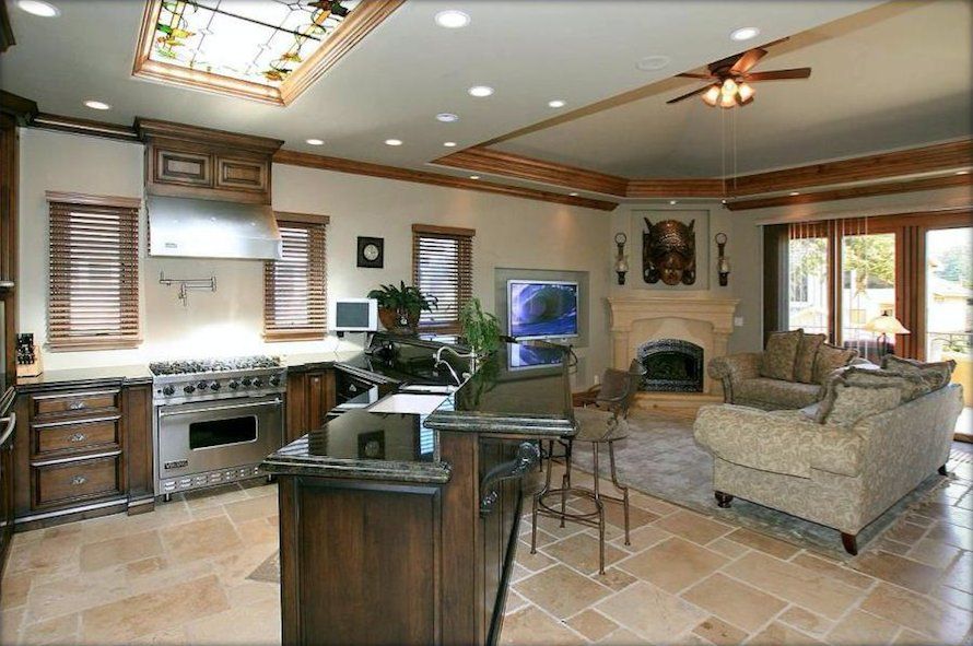 A kitchen and living room in a house with a ceiling fan