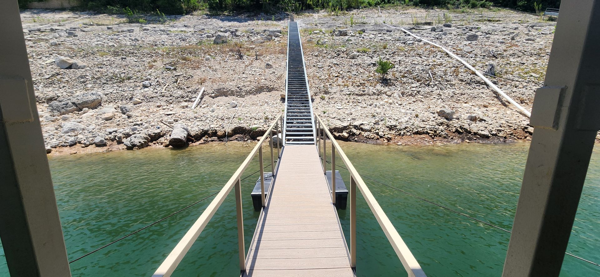 Wooden bridge over turquoise water, leading to a rocky shore.