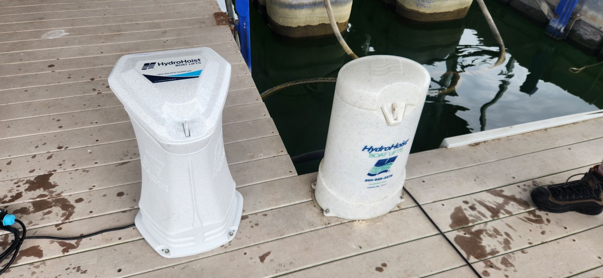 Two white water filters on a wooden dock next to water.