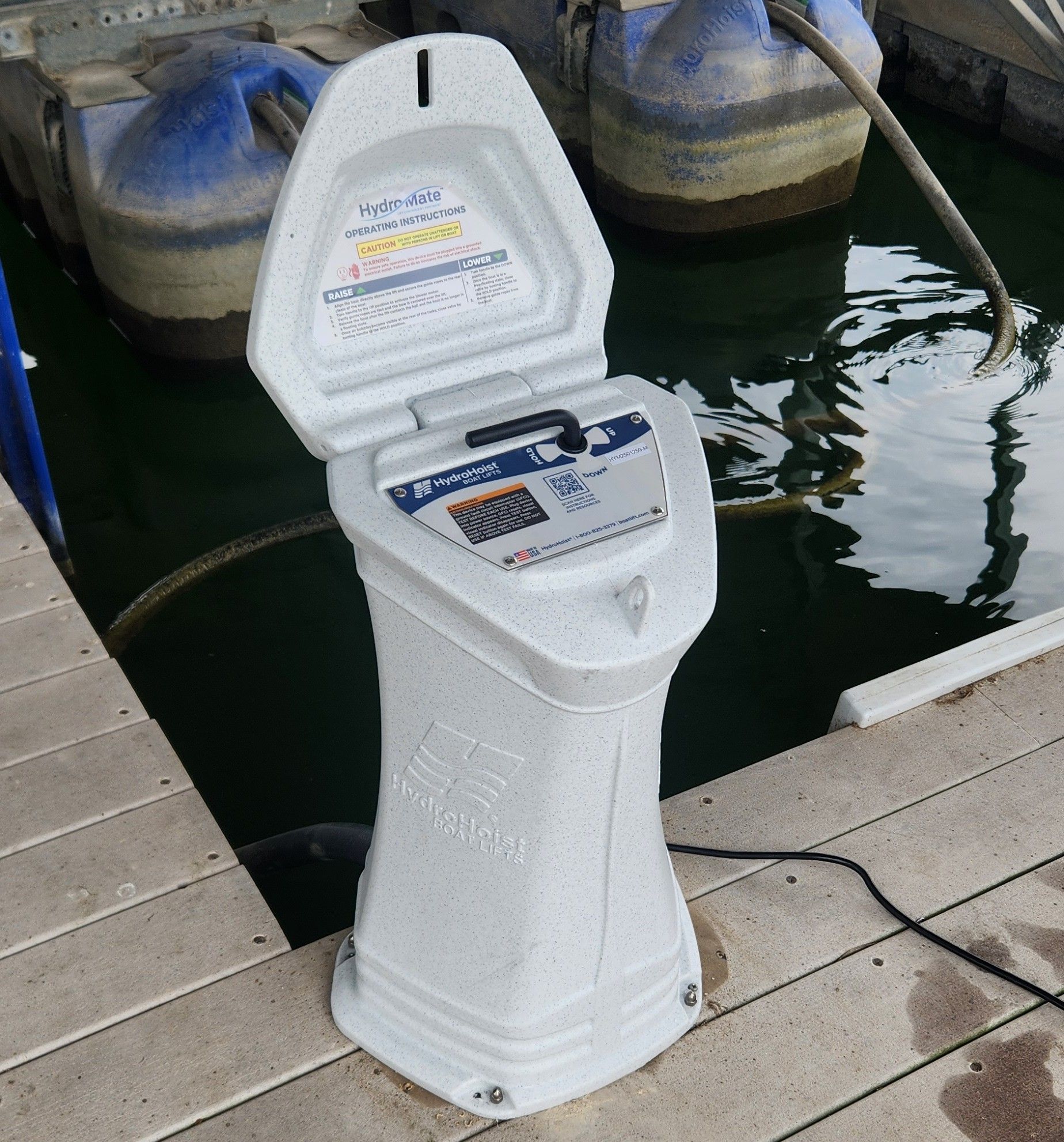 Dockside electrical pedestal with open door, next to water.
