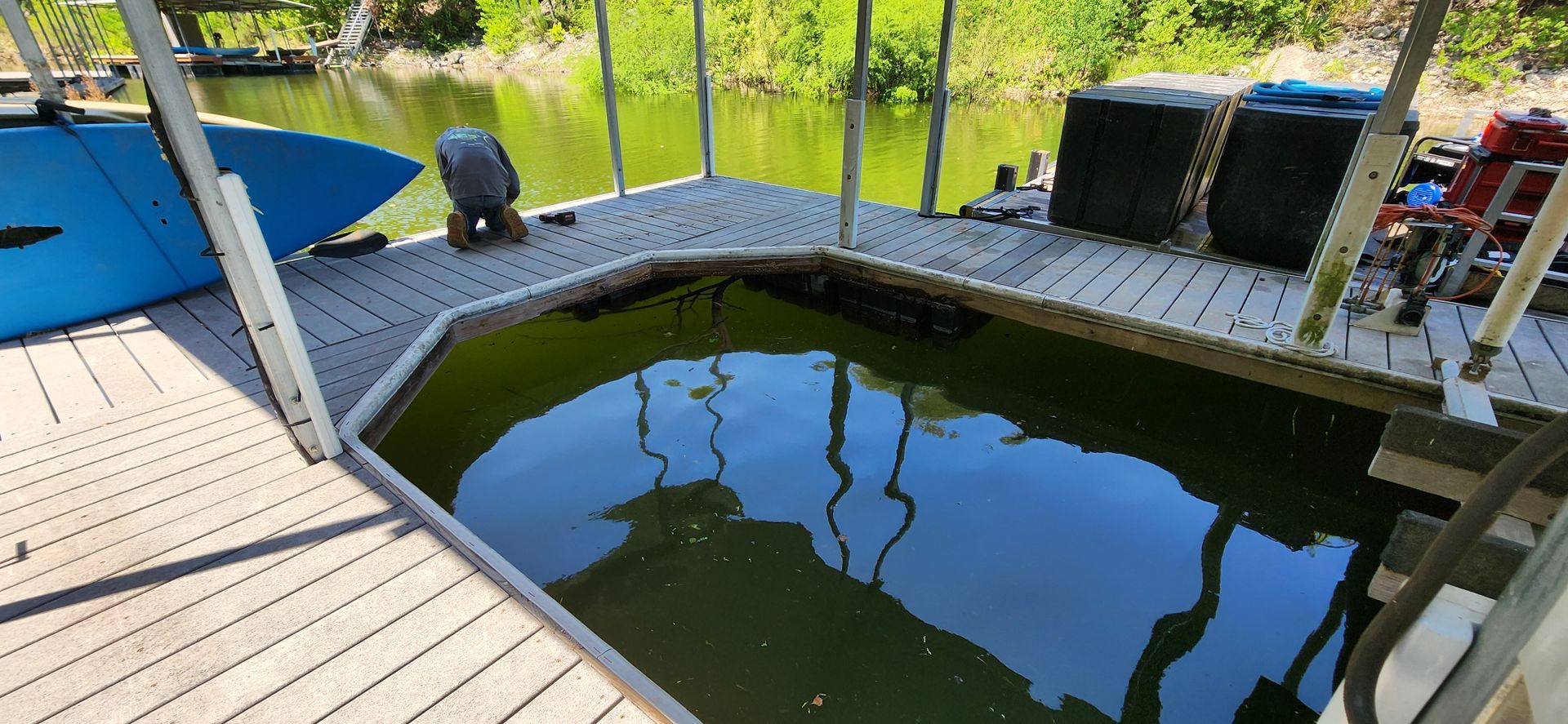 Dock with green water basin and surrounding deck. Blue boat visible.