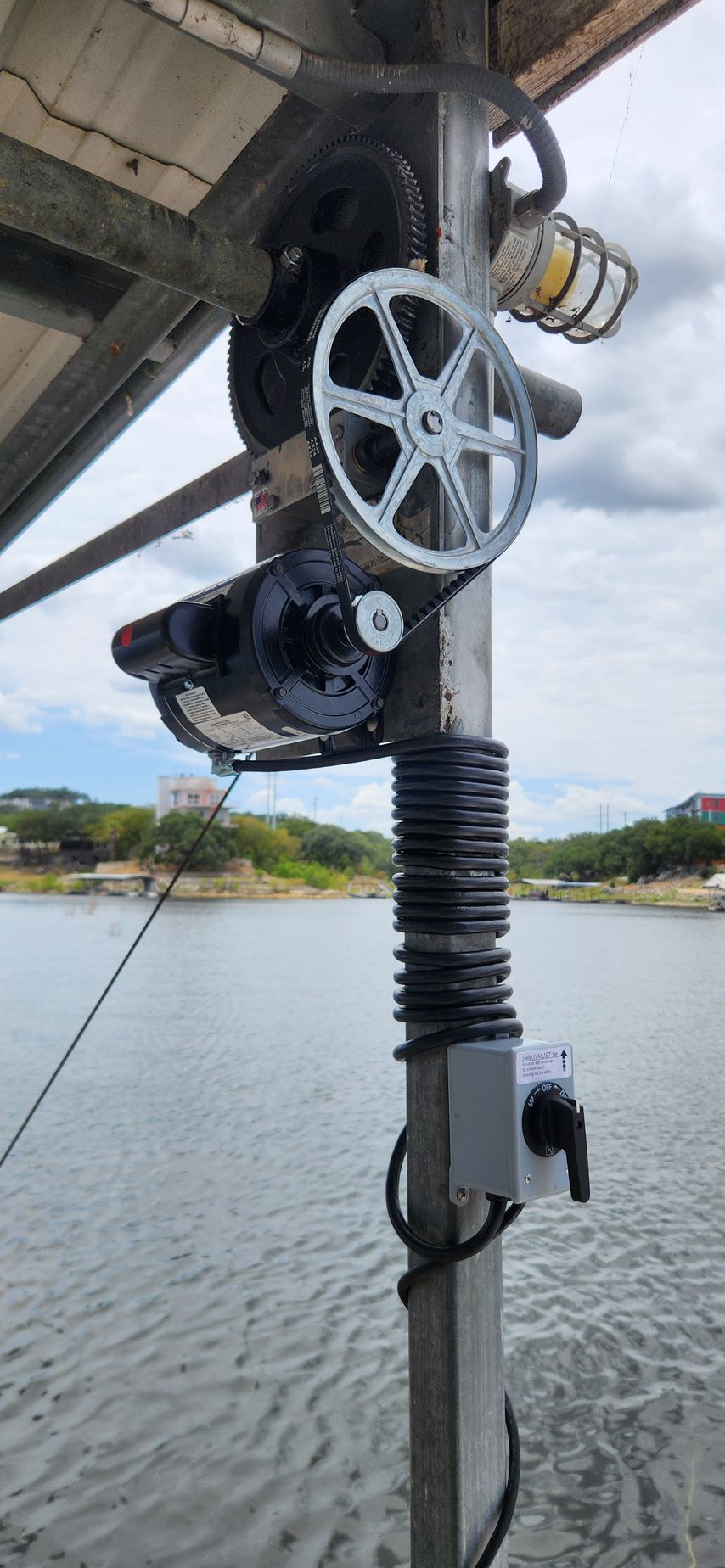 A metal structure with gears and a light, next to a body of water.