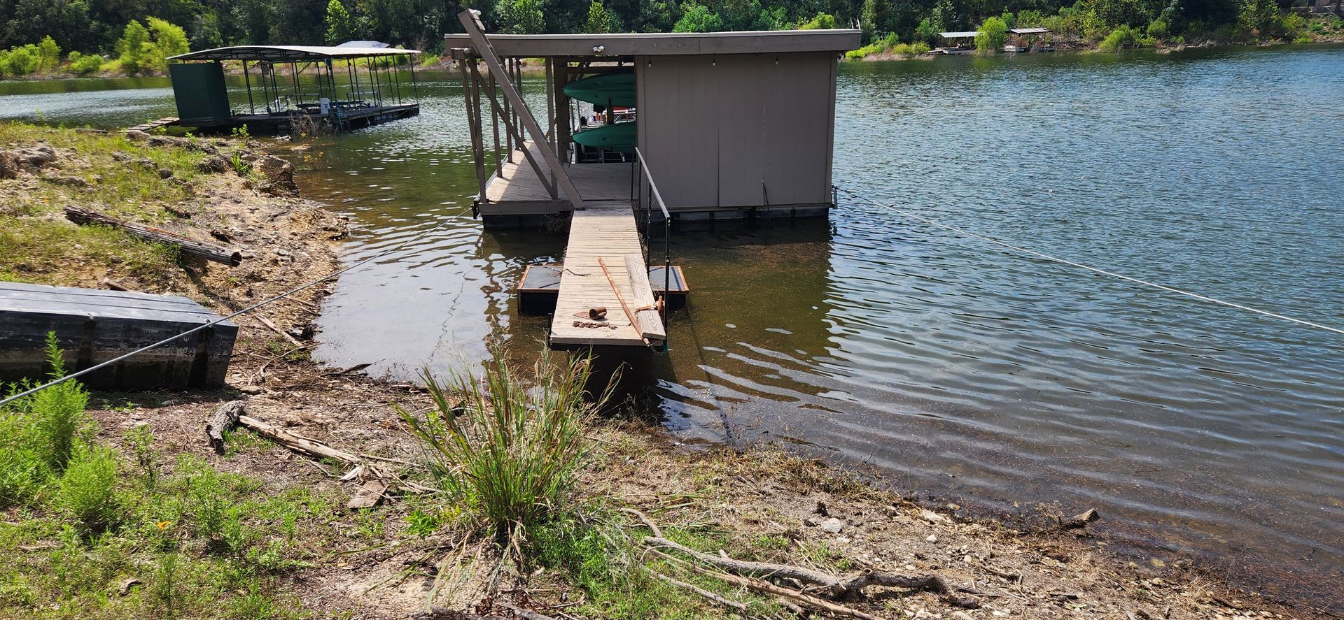 A wooden dock and boathouse on a lake with trees in the background.