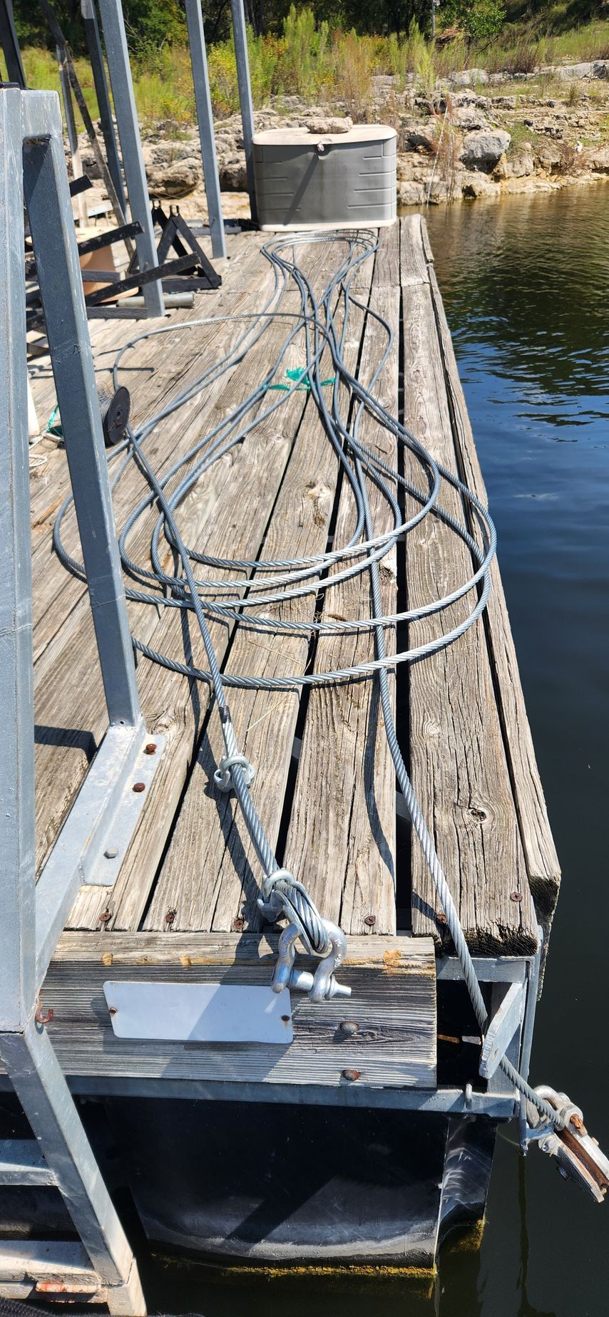 Wooden dock with coiled cables and a metal support structure over water.