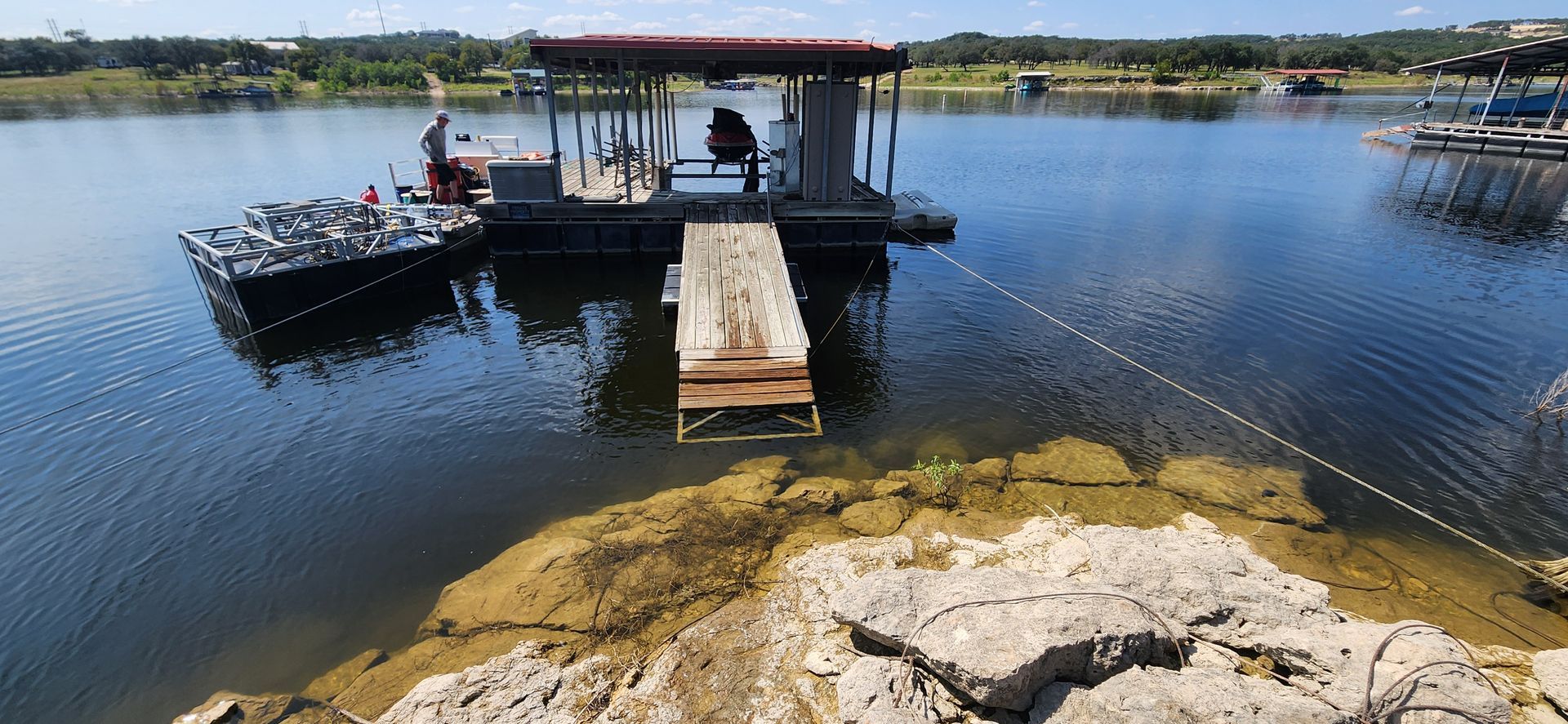 A boat docked at a floating platform on a lake.  A person stands on the platform.