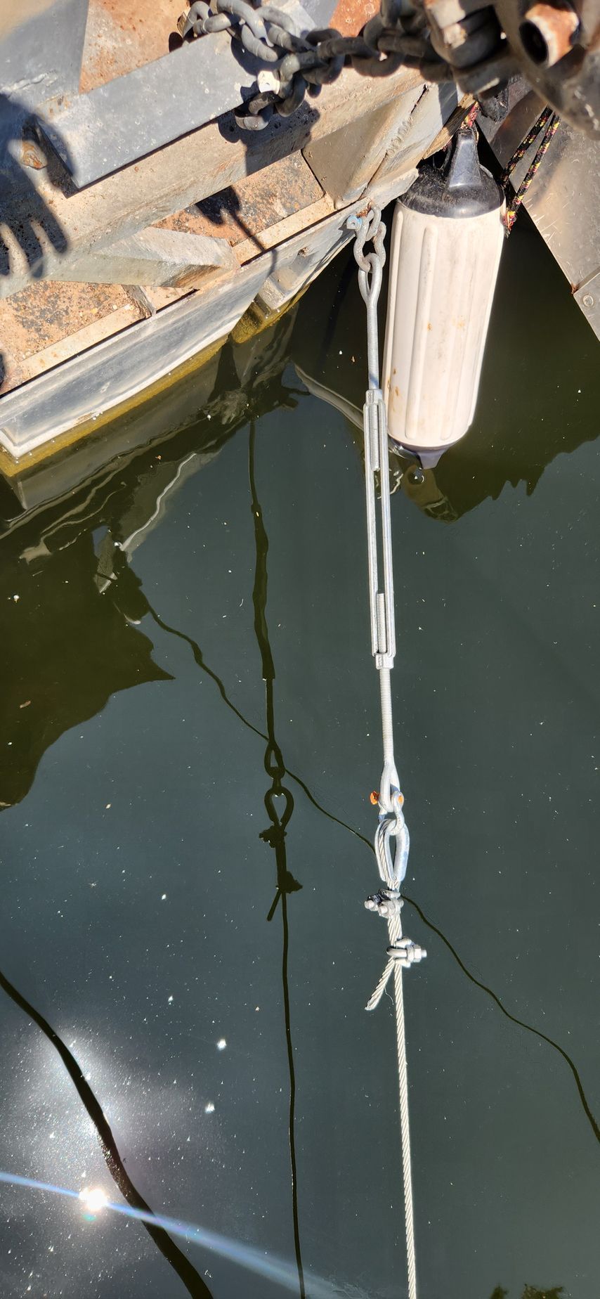 A rope, metal and wood structure extending into dark water, likely a dock or pier.
