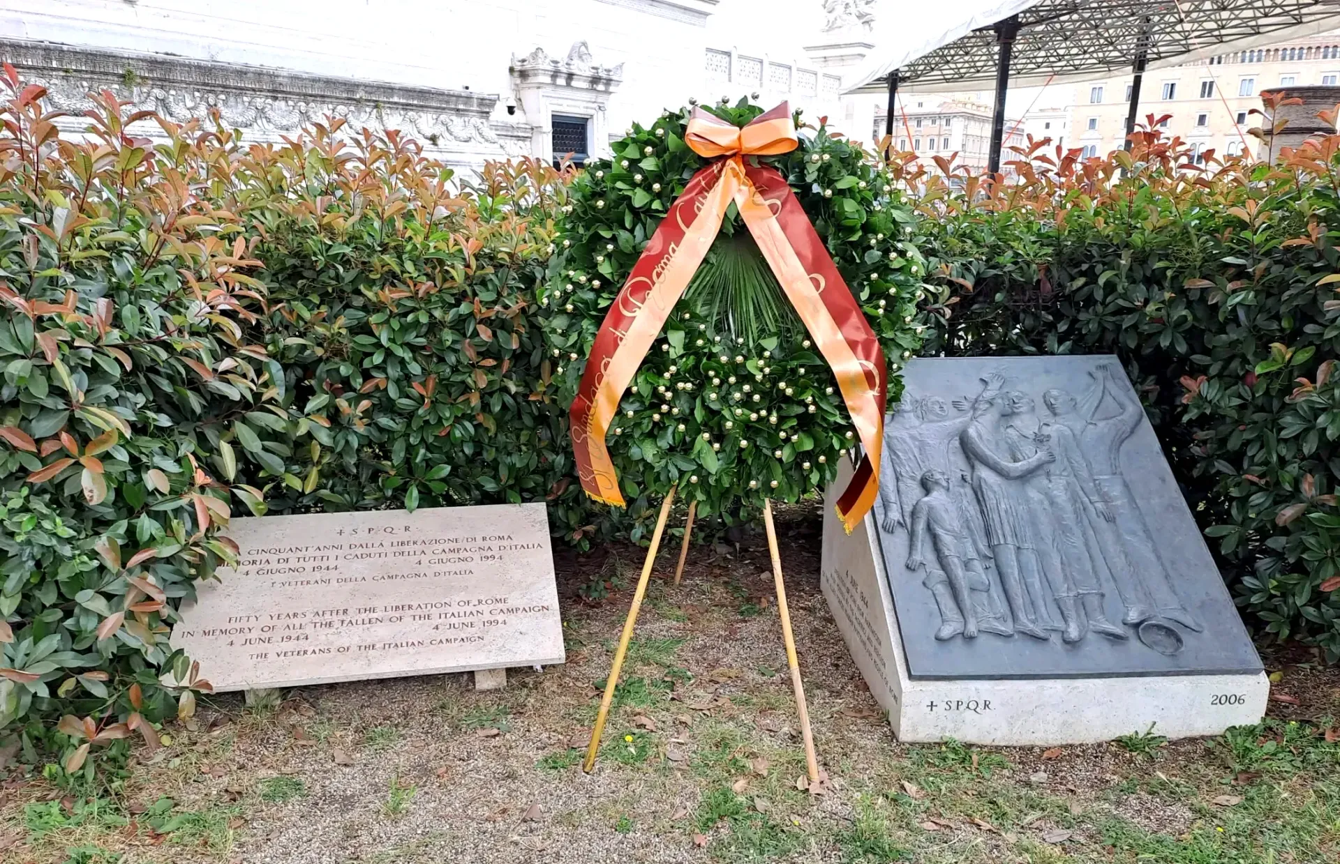 Memorial with wreath, stone plaques, and greenery.