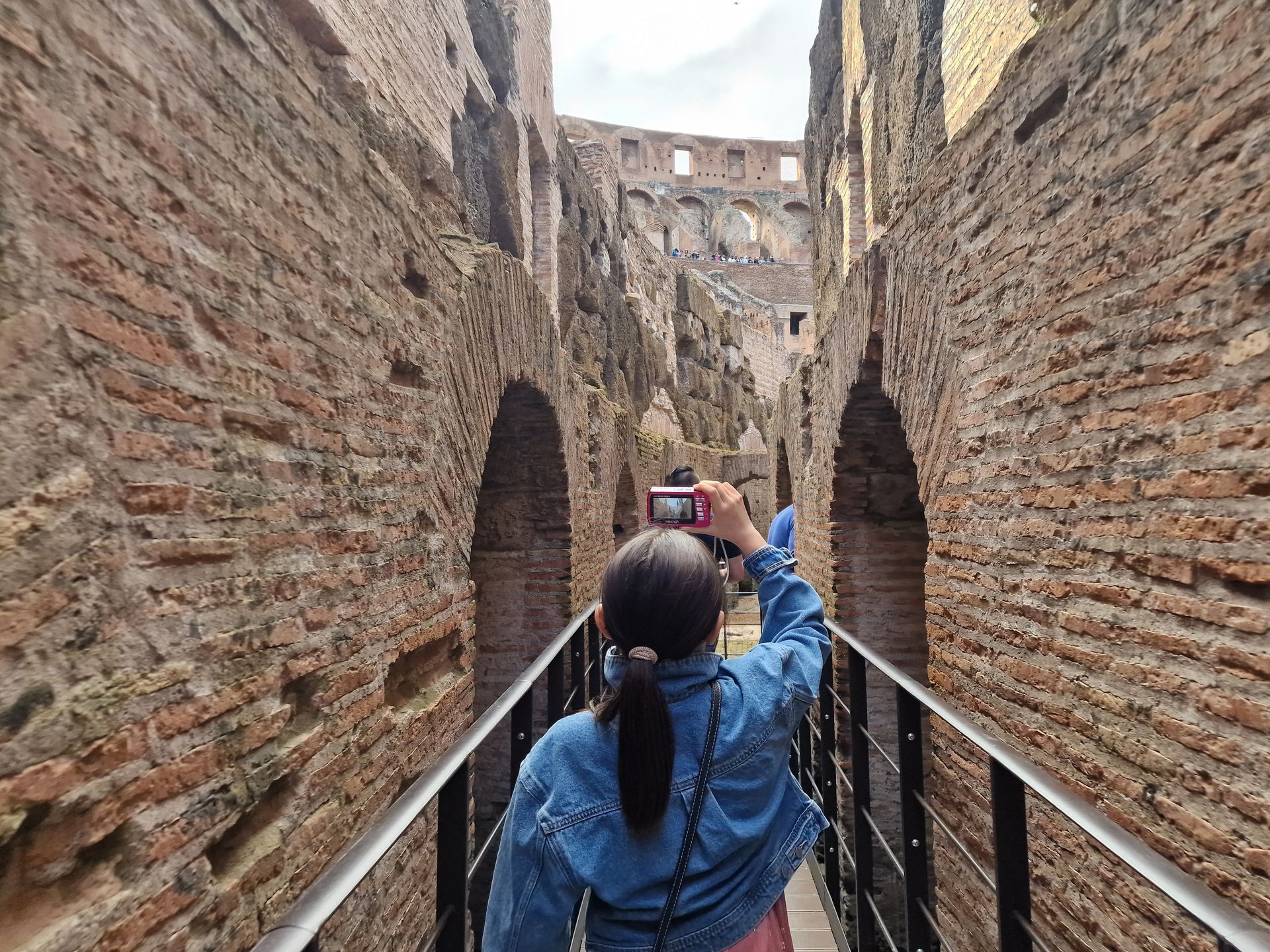 View through an archway into the Colosseum, Rome. Brick walls and architectural details are visible.