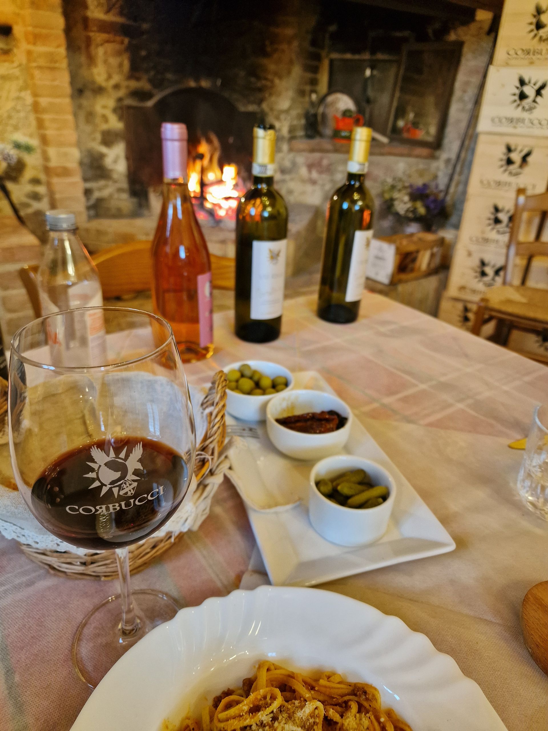 Food and wine on a table in front of a fireplace at a wine tasting in a villa in Tuscany.