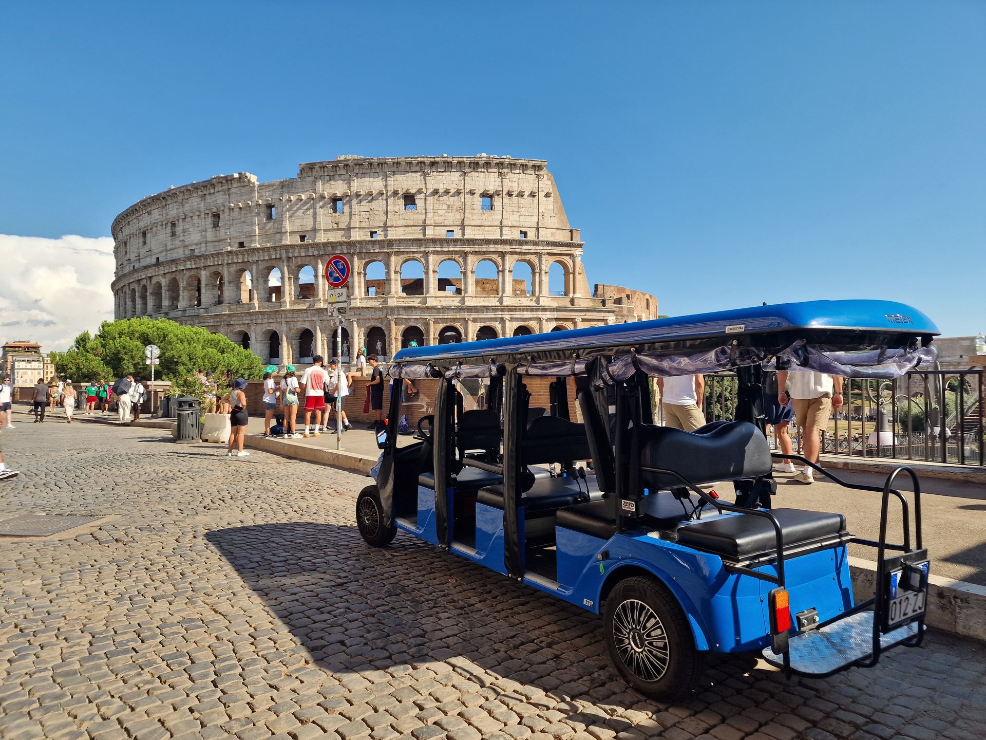 Cobblestone street in Rome, Italy with the Colosseum and a golf cart tour