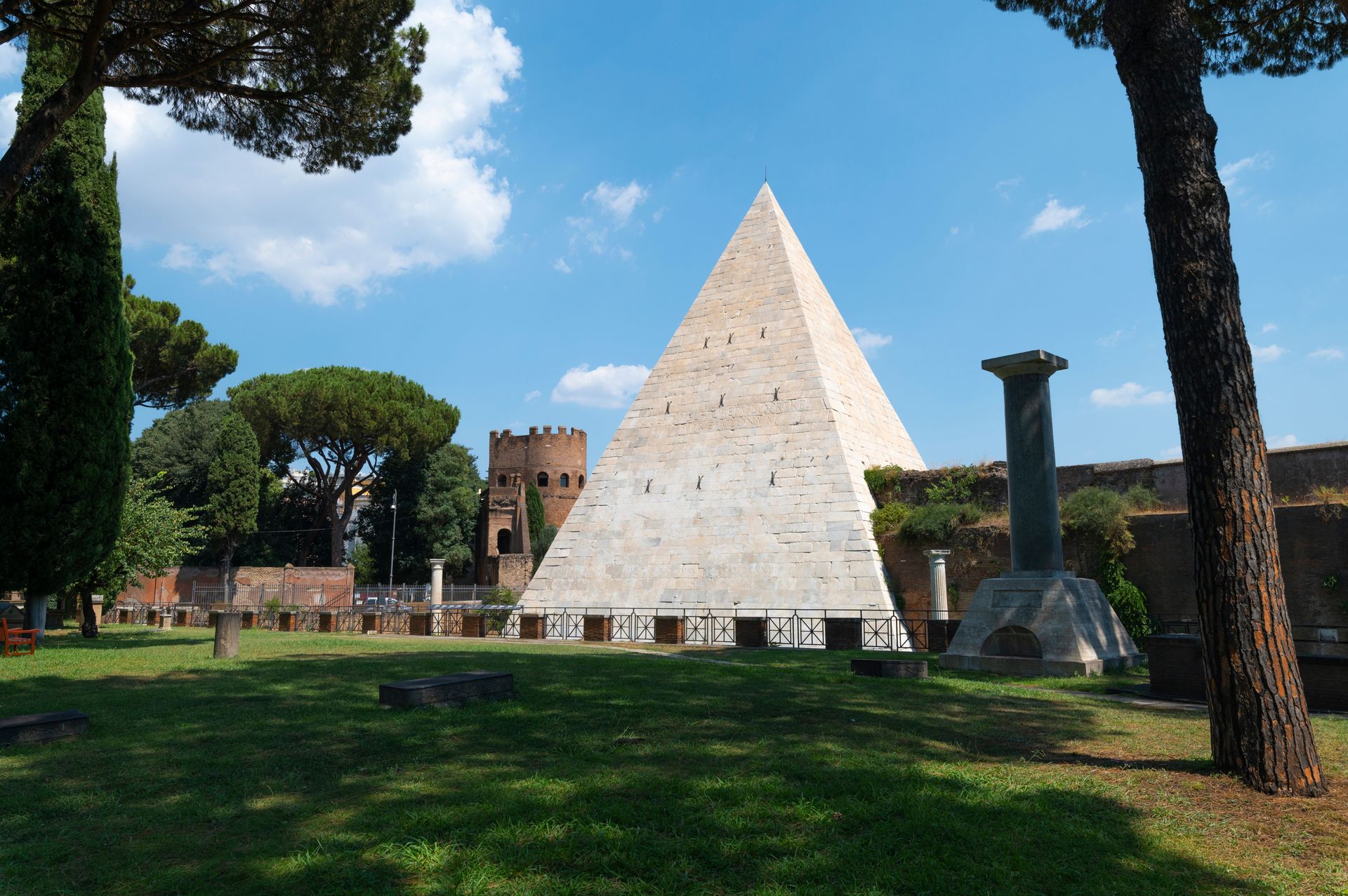 Pyramid of Cestius in Rome, Italy, with green lawn and blue sky.