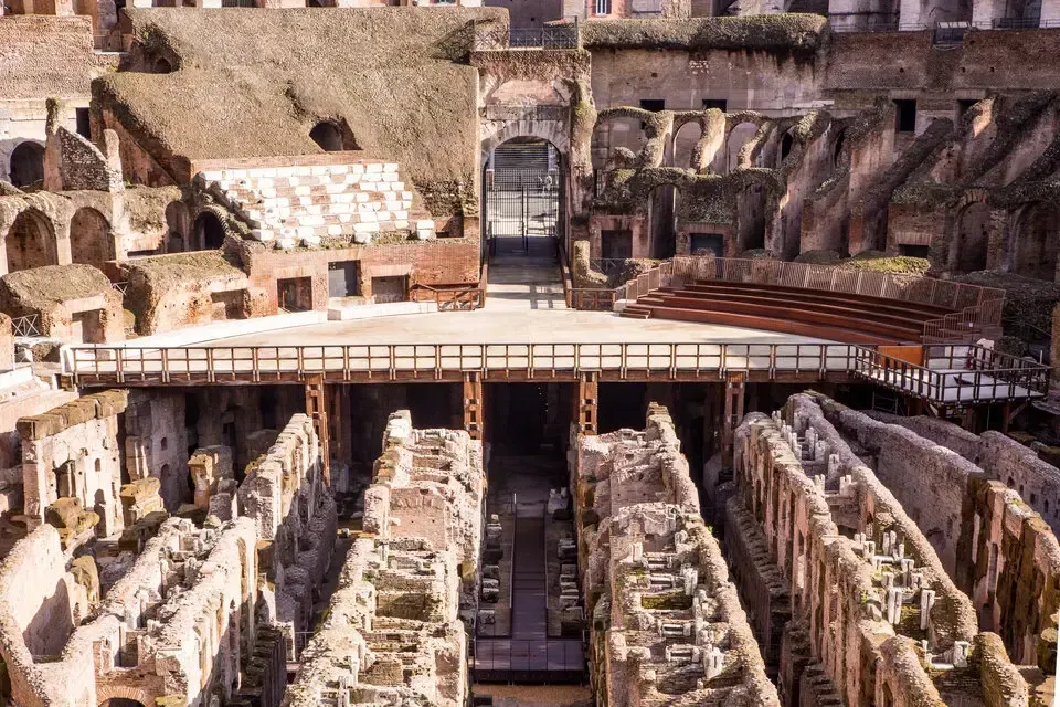 An old, tiered building in Rome with arches, columns, and greenery.
