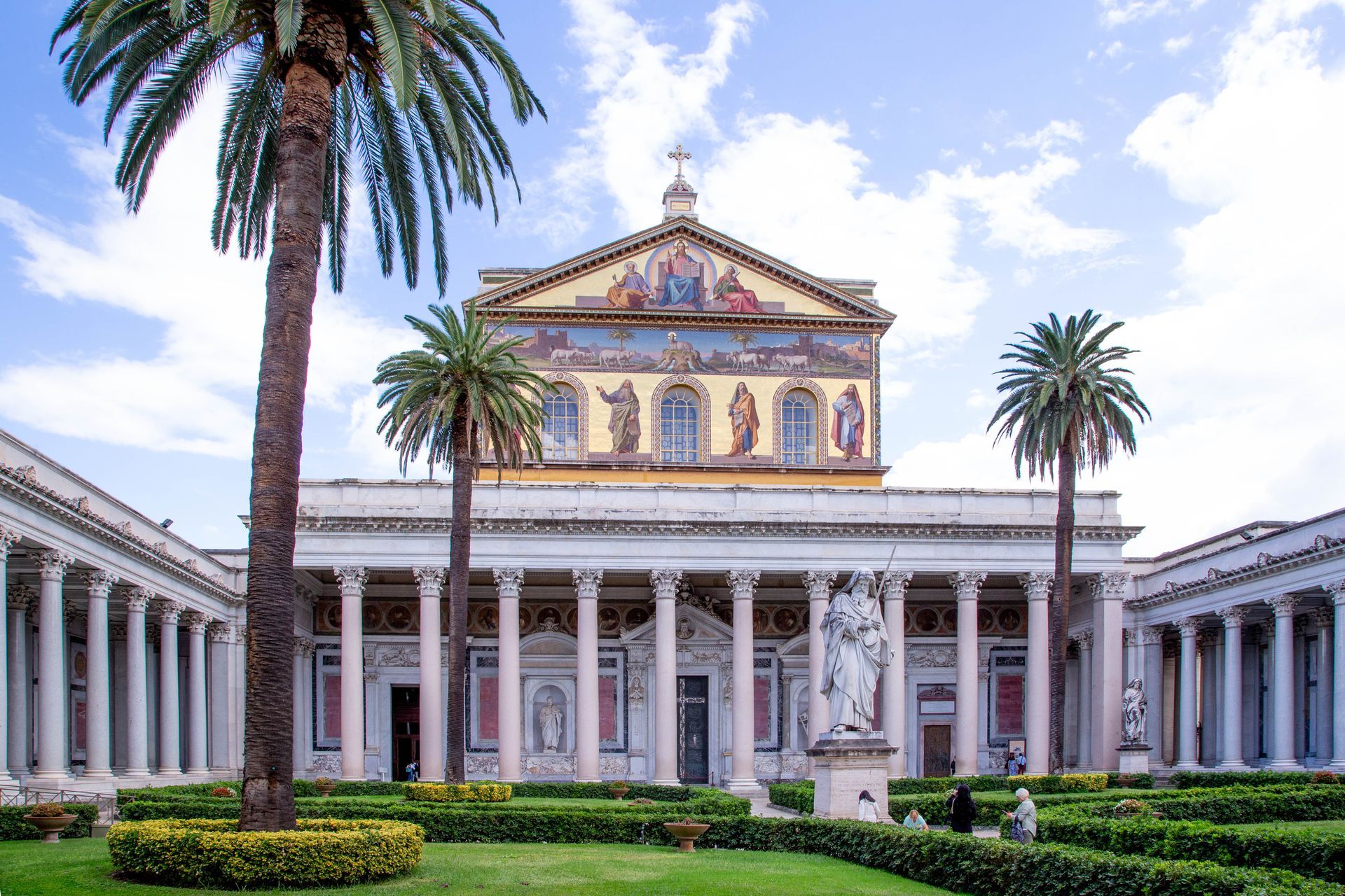 St. Peter's Basilica, Rome, seen through tree branches; dome dominates skyline under a clear, blue sky.