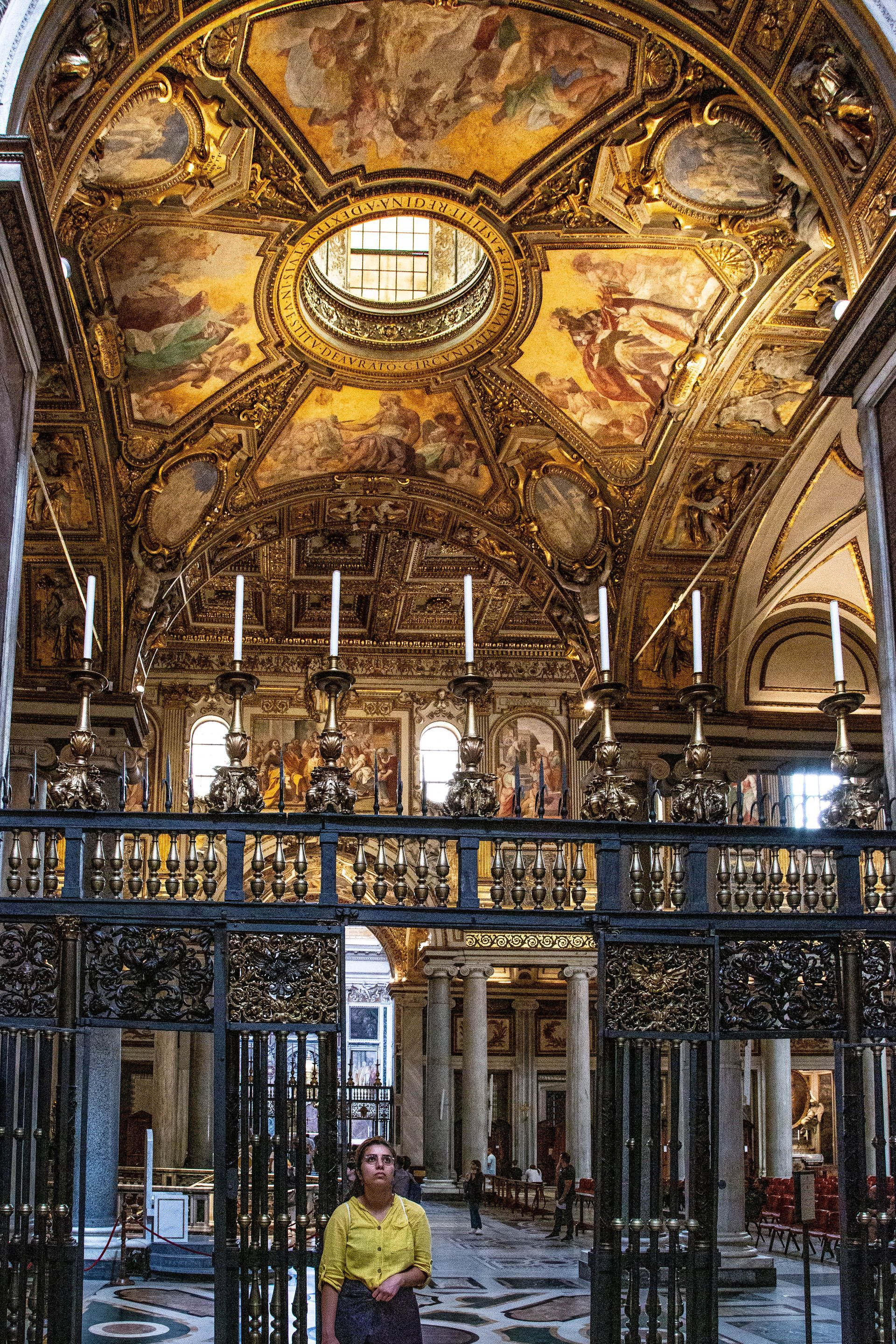 St. Peter's Basilica in Vatican City, seen from afar, with its iconic dome and framed by trees.