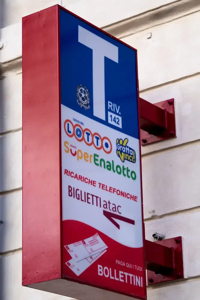 Sign for lottery and ticket sales with a red frame and blue and white panels.