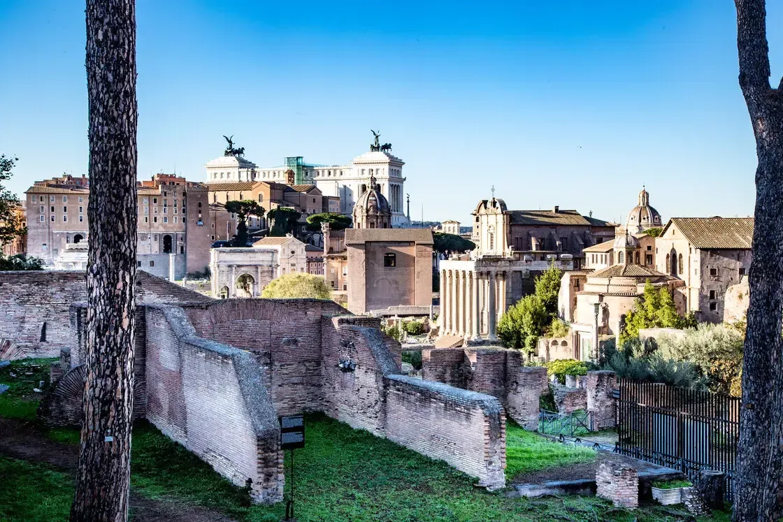 Ancient ruins and buildings in Rome under a clear blue sky.