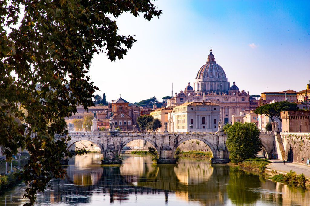 Bridge over calm water, St. Peter's Basilica dome in distance, Rome, Italy.