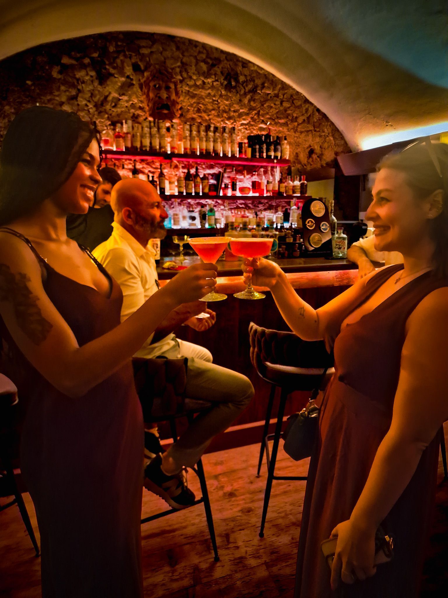 Romantic couple with ancient Roman ruins with tall columns, backlit by the sun, set behind a metal fence and red flowers.