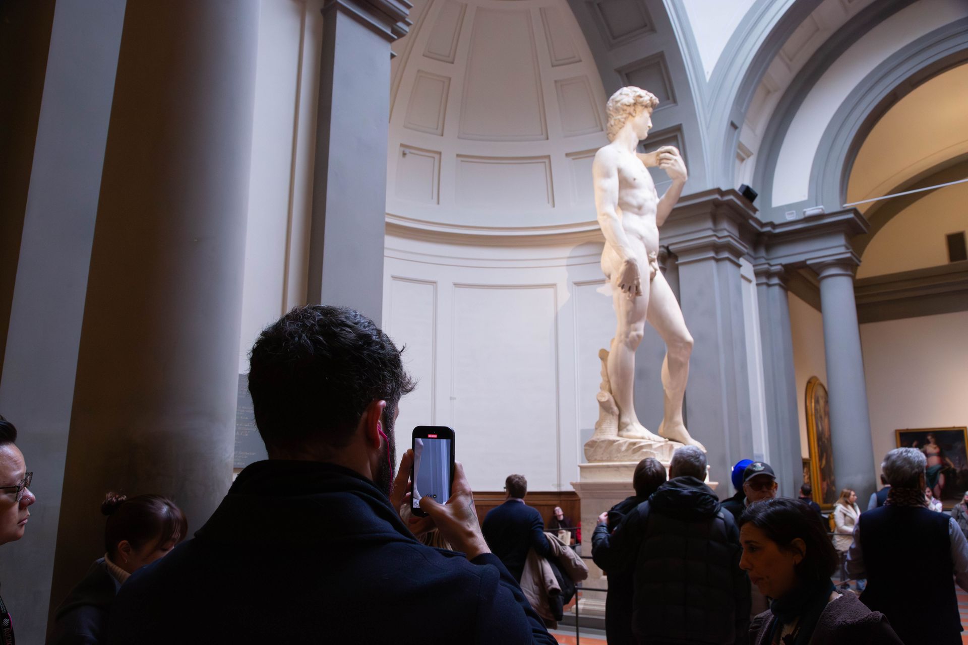 Person taking a photo of the David statue in Florence.