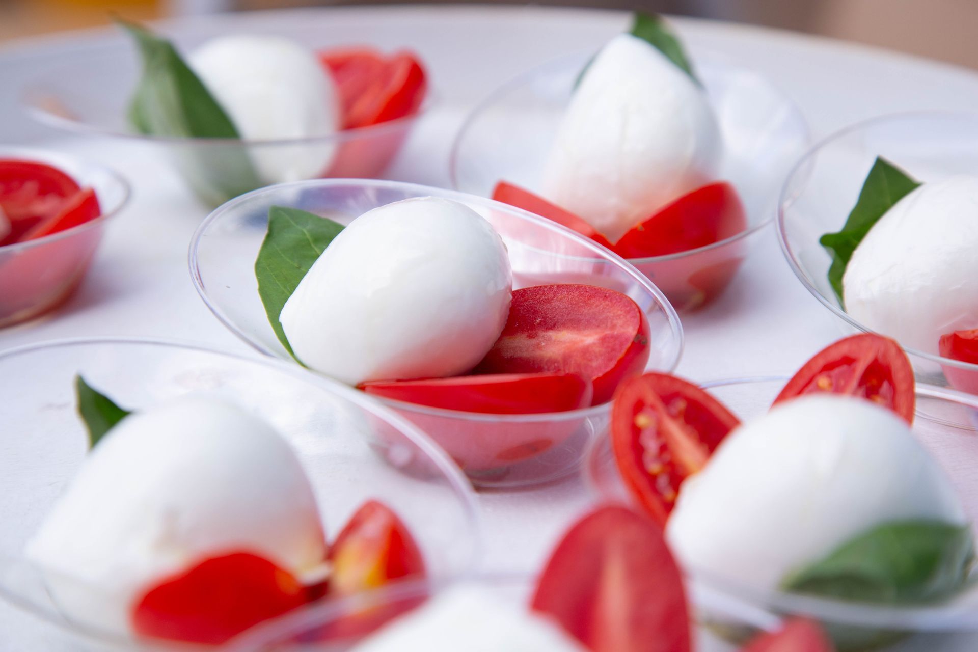 Man cutting cheese at a market stall, smiling, wearing a London shirt and apron.