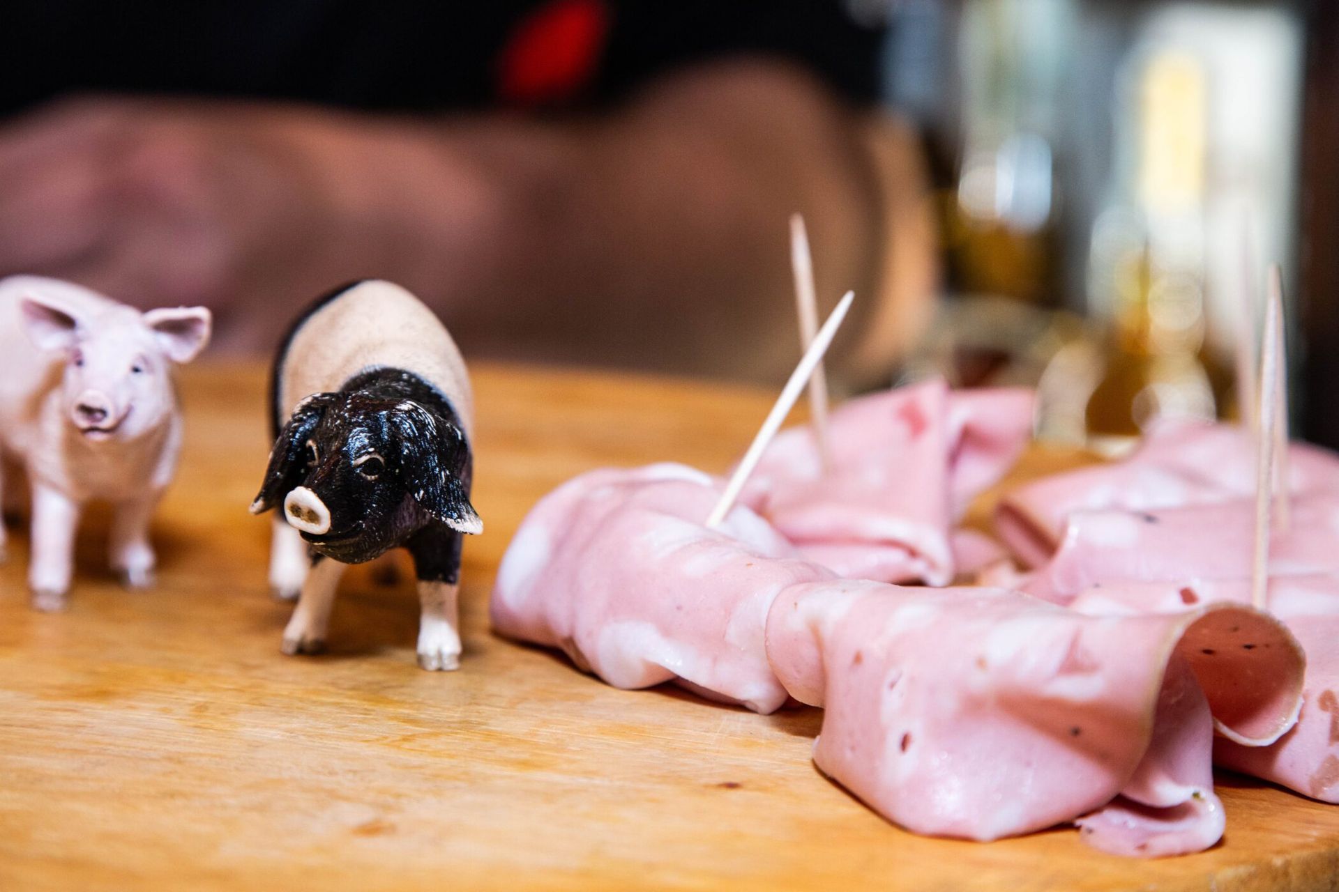 People browsing in a crowded Italian deli filled with hanging cured meats and packaged cheeses.
