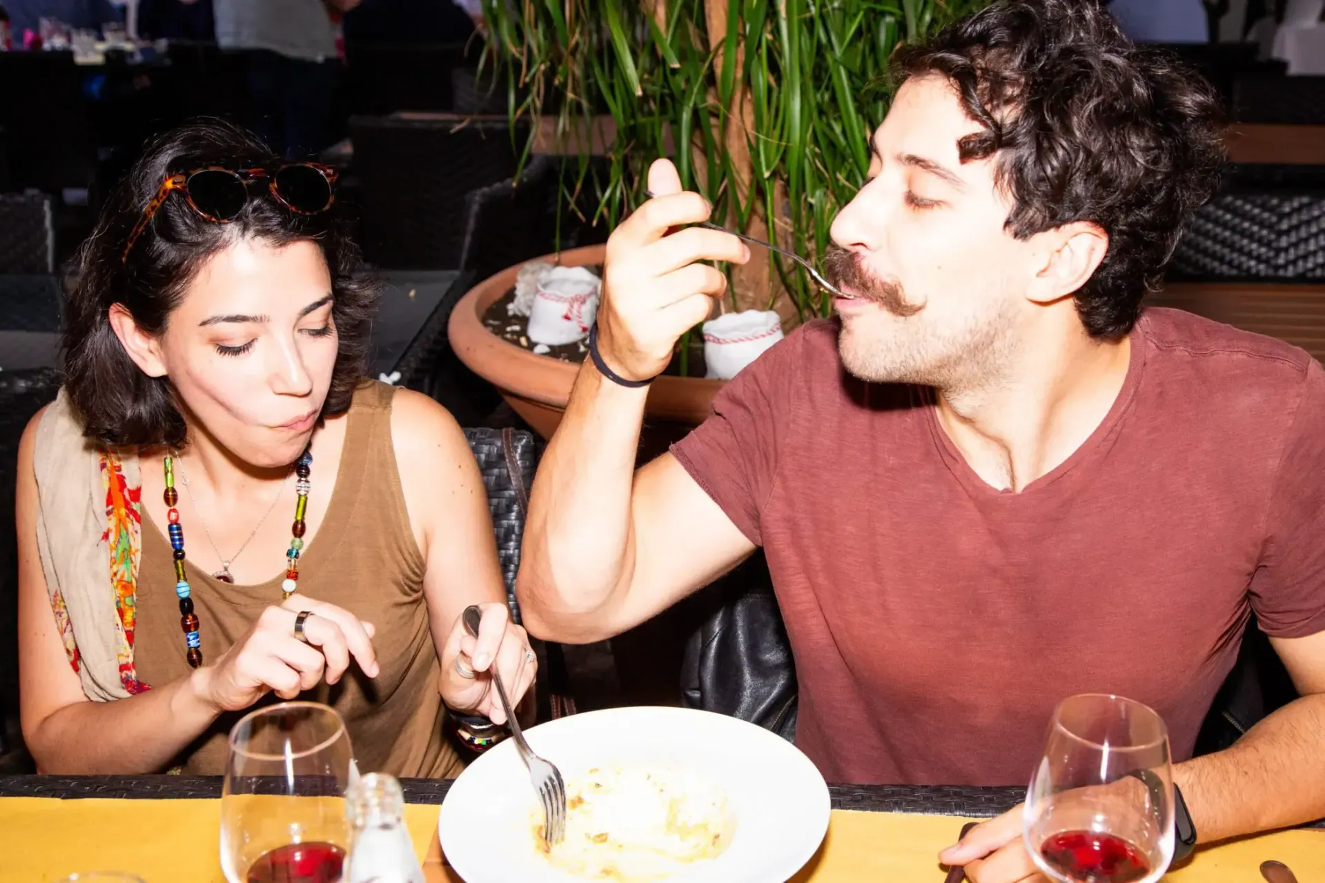Man cutting cheese at a market stall, smiling, wearing a London shirt and apron.