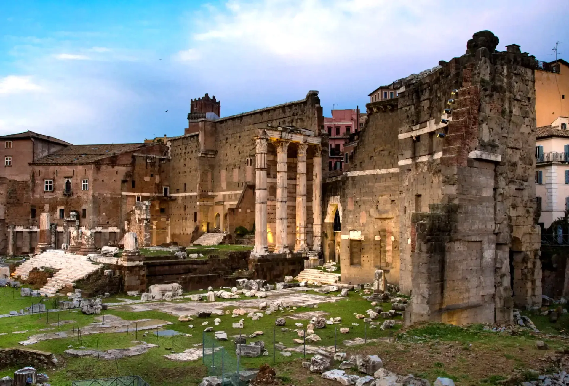 Ruins of ancient Roman structures with columns, against a cloudy sky.