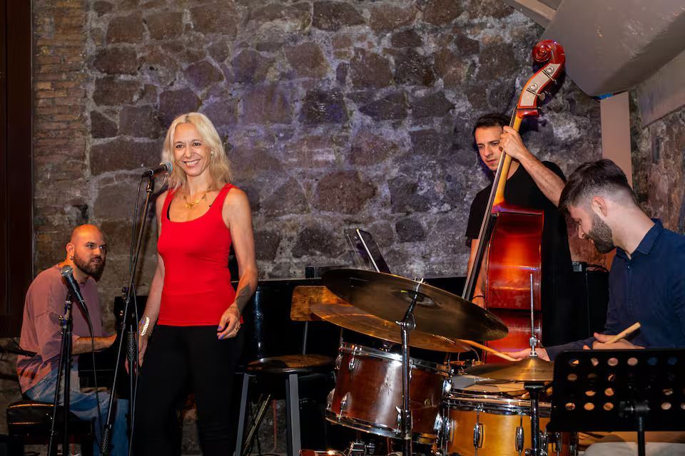 Romantic couple with ancient Roman ruins with tall columns, backlit by the sun, set behind a metal fence and red flowers.
