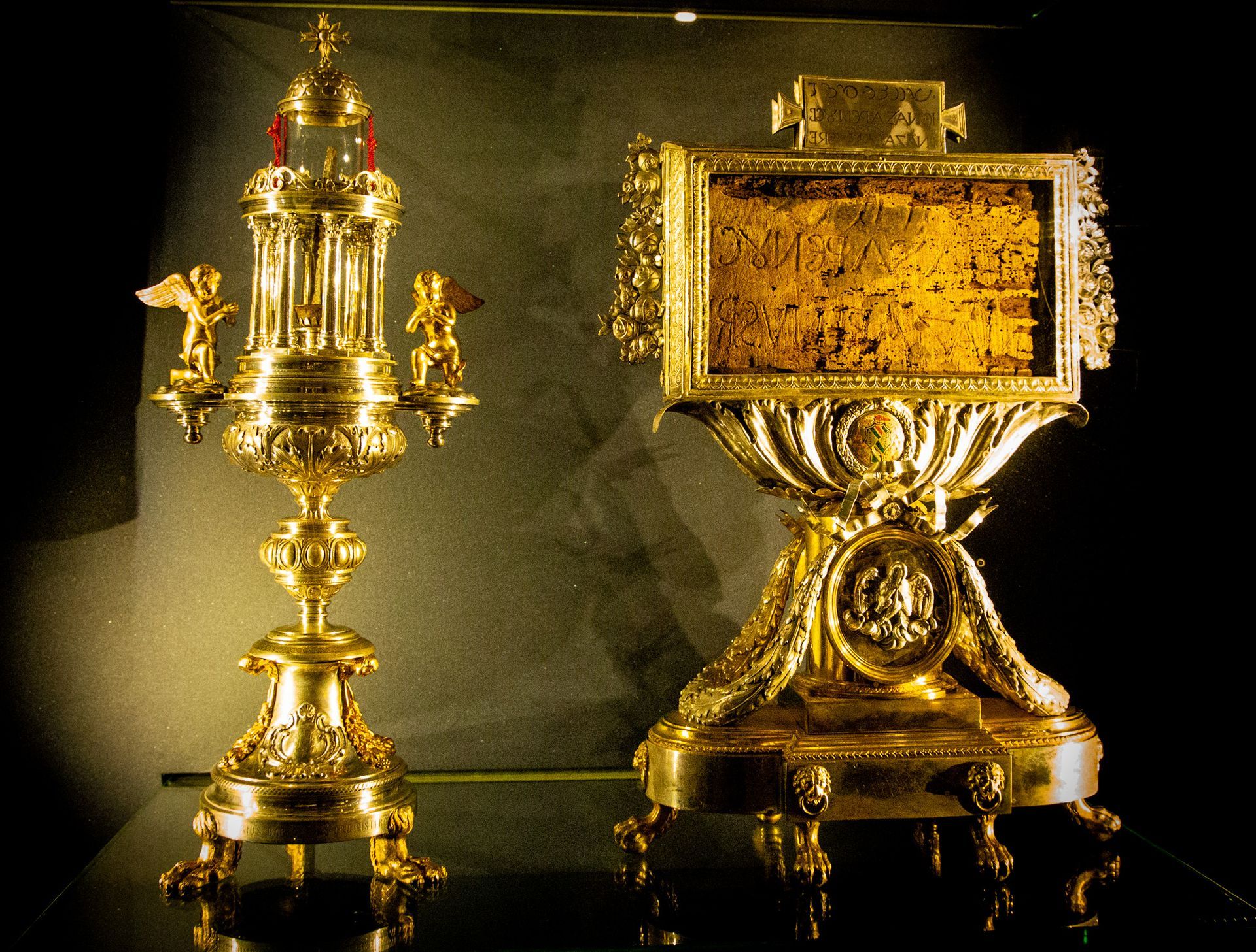 Stone bridge with statues over a river in Rome, Italy. Buildings and trees line the banks under a cloudy sky.