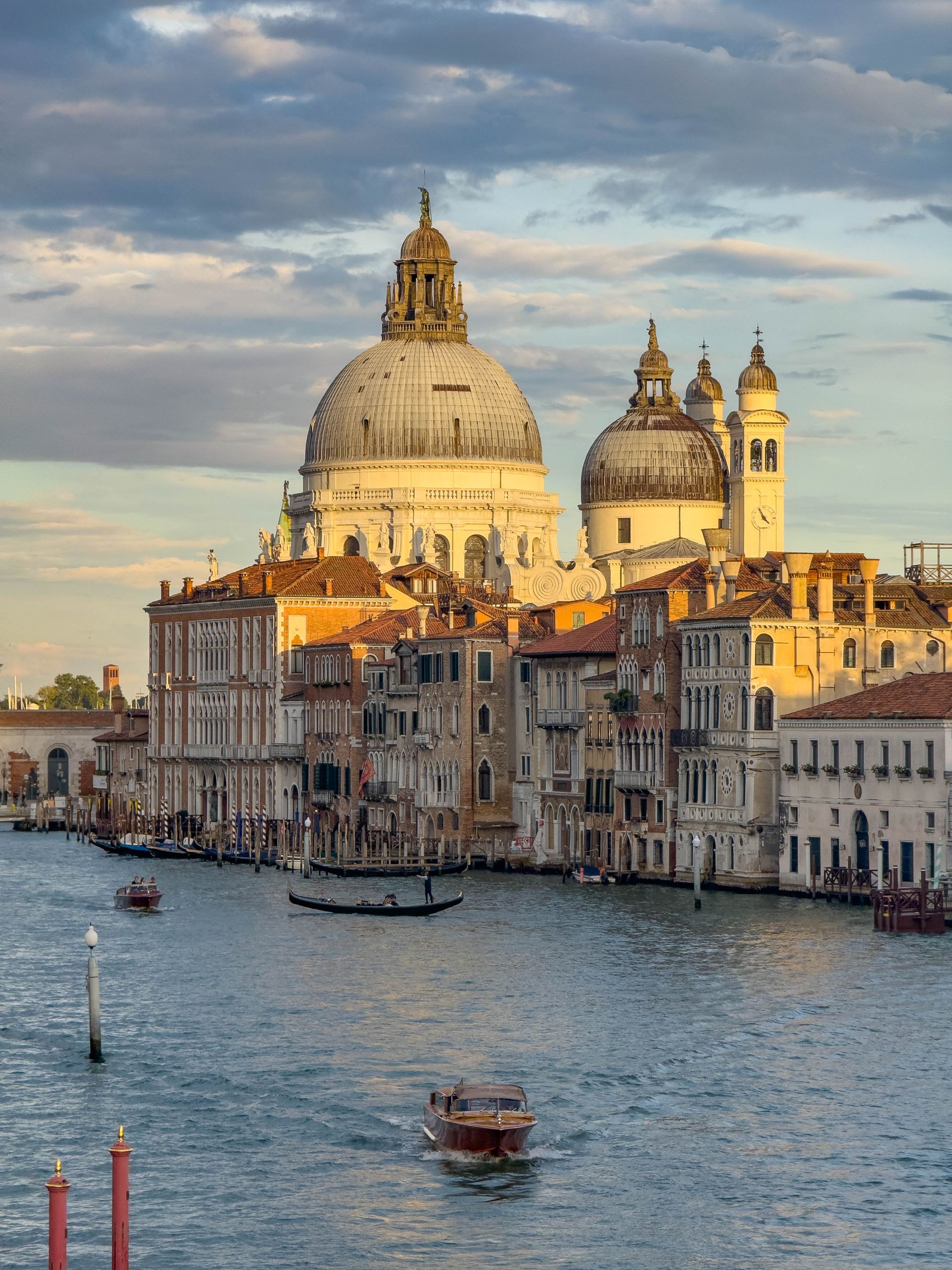 Boats on a canal passing by a church in Venice.