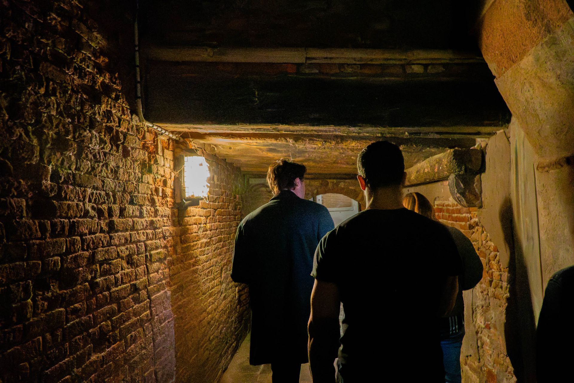 People walking down a dark alley in Venice at night.