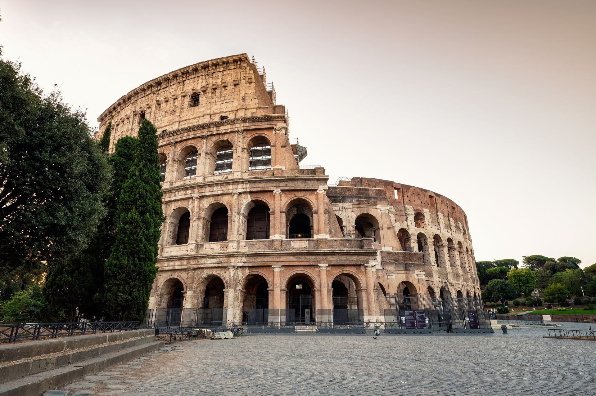 Colosseum in Rome, Italy, a large, weathered amphitheater with archways under a clear sky.