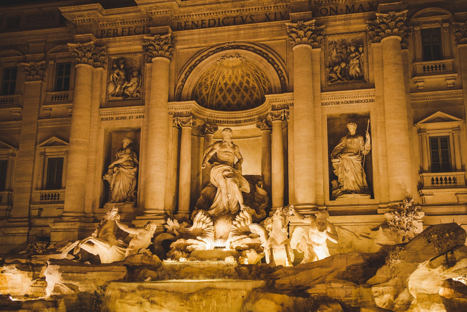 Pantheon at night, Rome, illuminated facade and fountain with obelisk, cobblestone plaza, buildings in background.