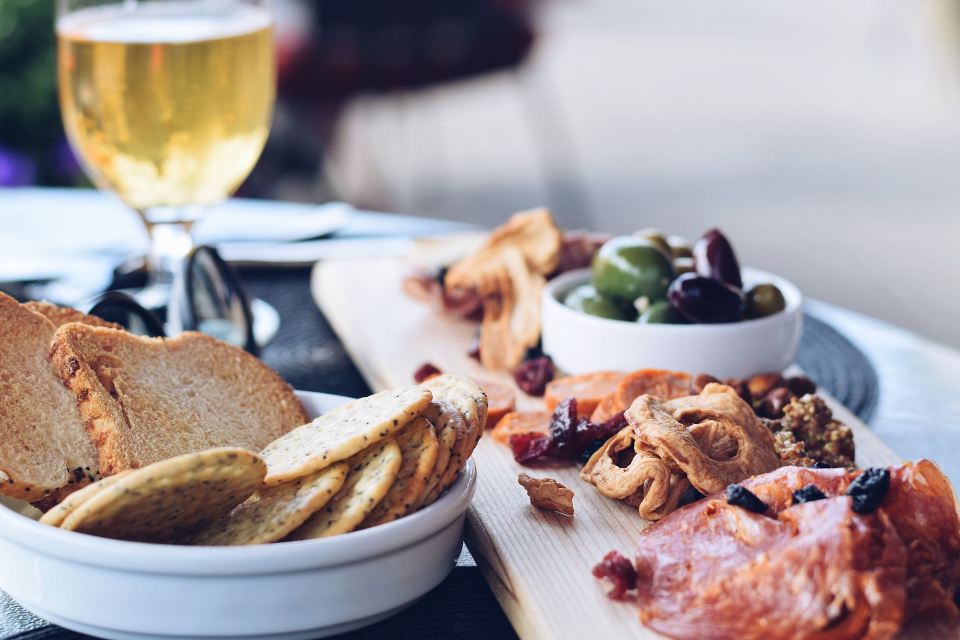 Charcuterie board with crackers, olives, and beer.