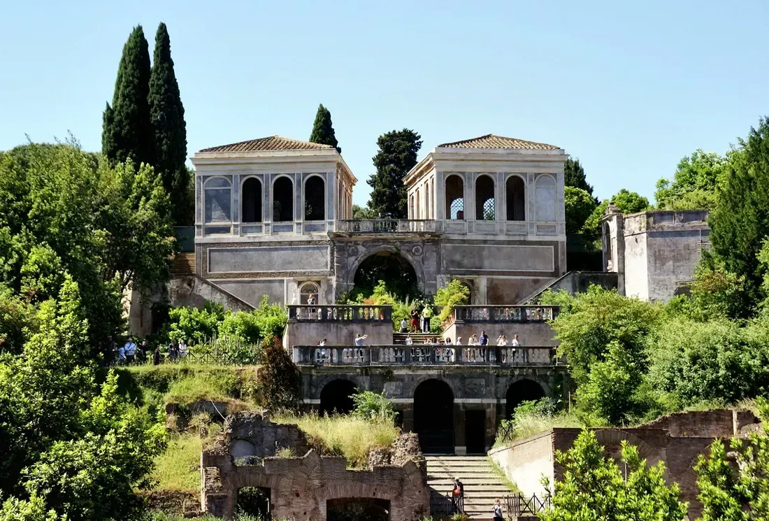 An old, tiered building in Rome with arches, columns, and greenery.