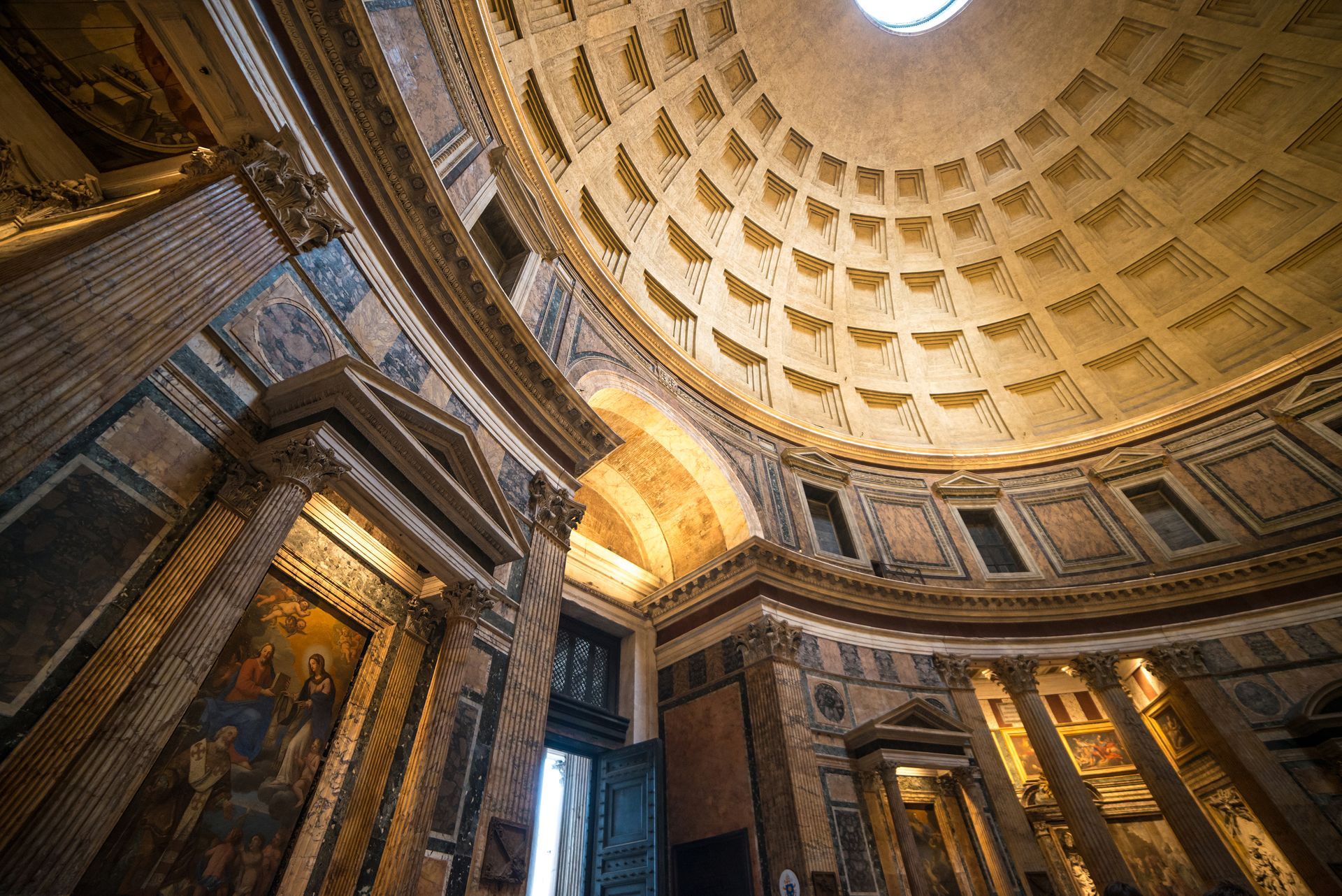 Interior of the Pantheon, Rome. Vast, domed ceiling with recessed panels, sunlight streams through the oculus.