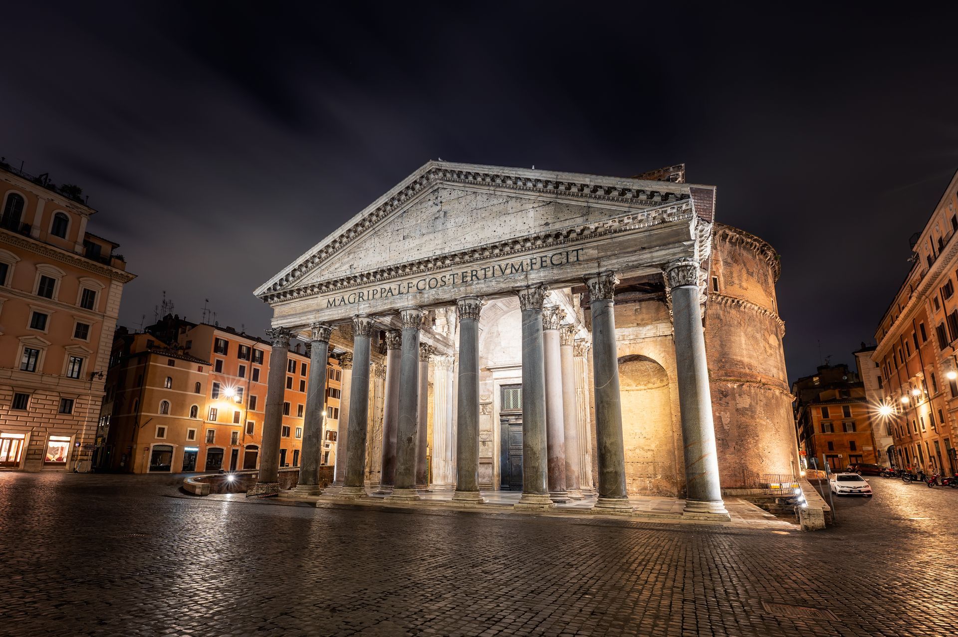 Trevi Fountain at night, Rome, illuminated. Baroque architecture, water, buildings frame it under a dark blue sky.