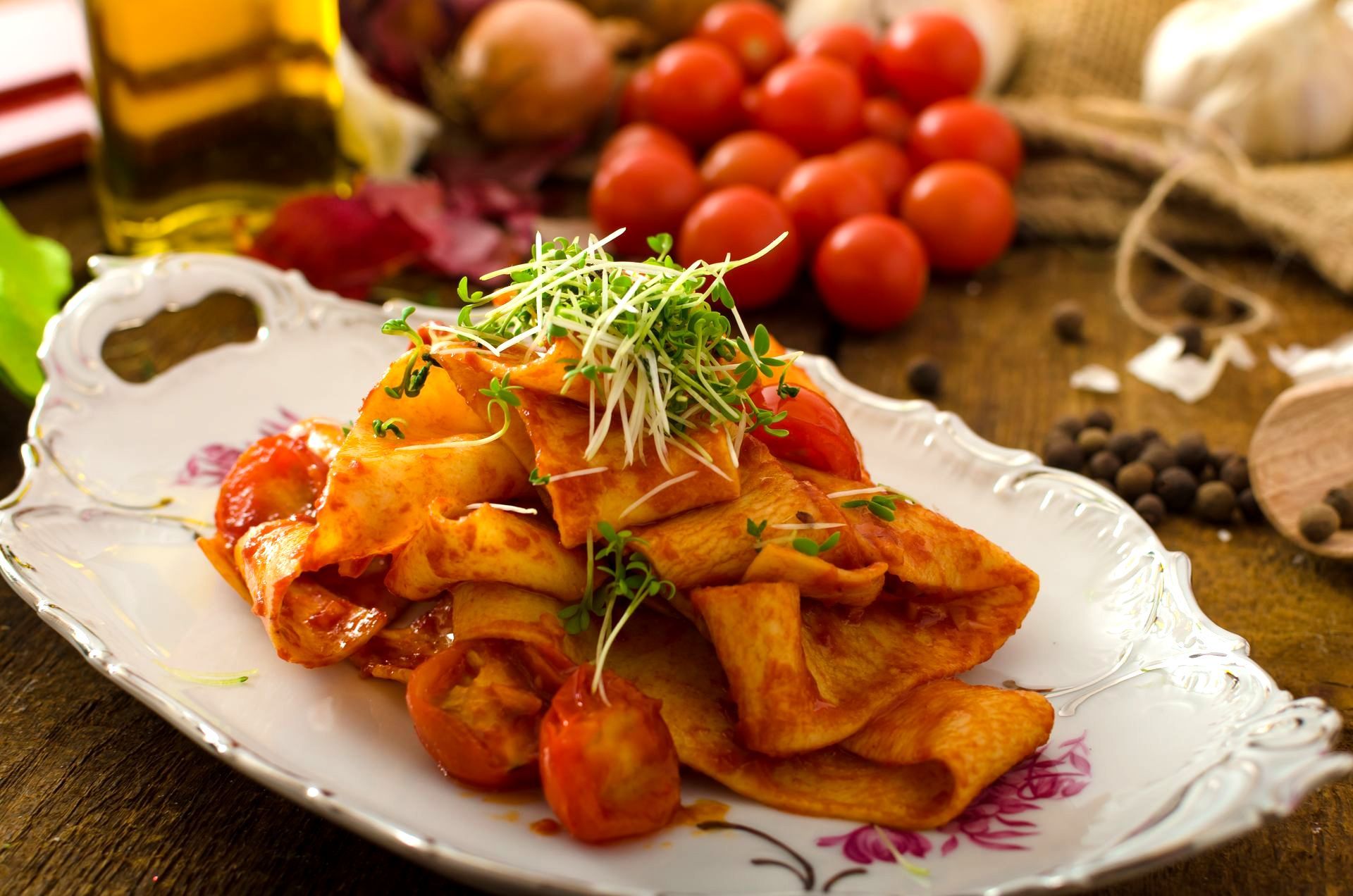 Pasta dish with cherry tomatoes and sprouts on decorative plate.