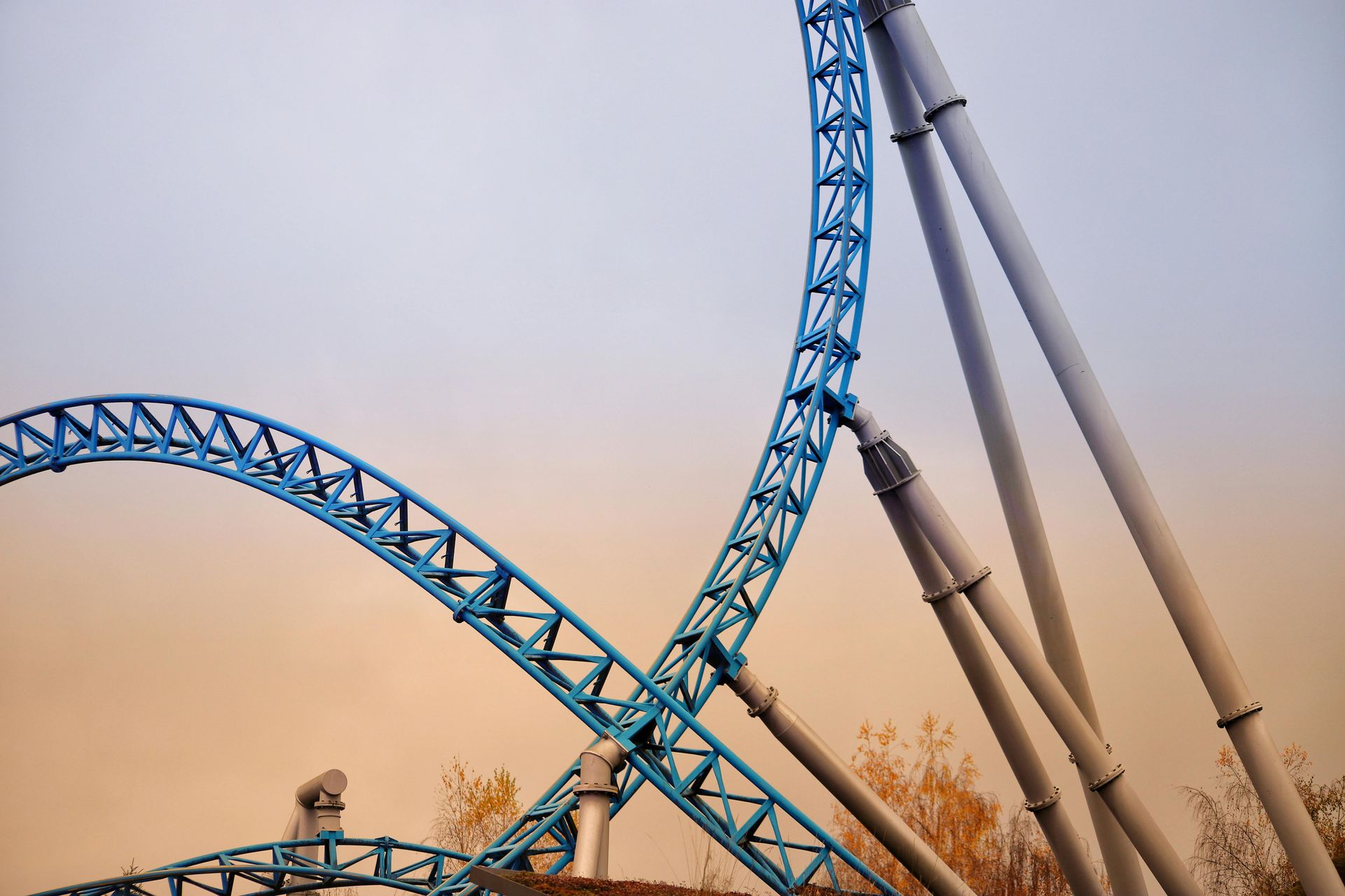 Blue roller coaster track against an overcast sky.