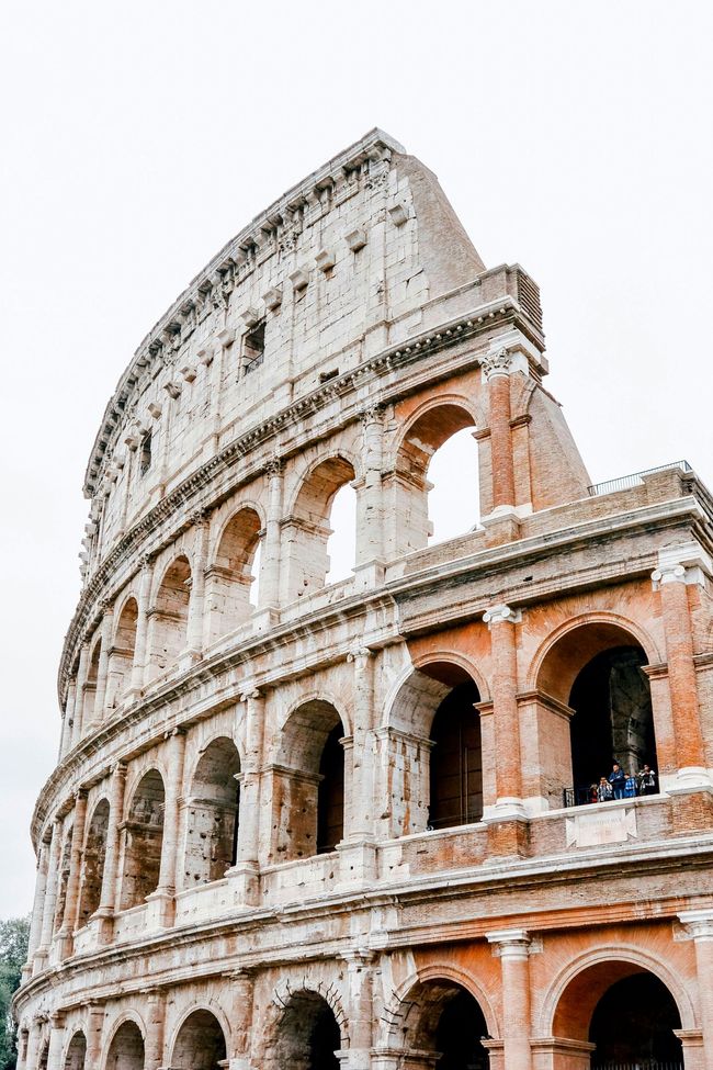 Colosseum, Rome, Italy. Ancient amphitheater with arched openings; brick and stone construction. Cloudy sky.