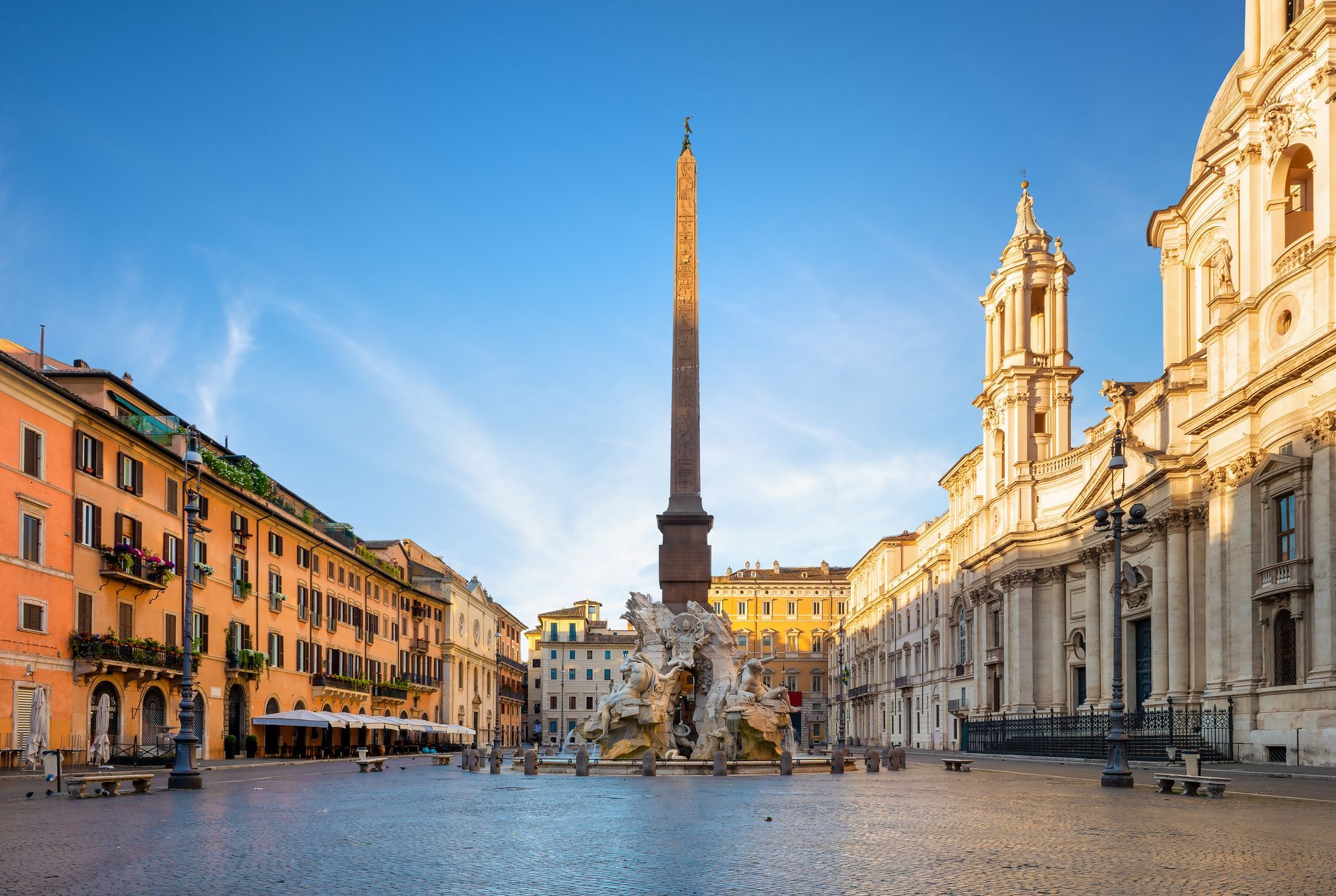 Piazza Navona in Rome, Italy, with an obelisk and fountain in the center. Buildings surround the cobblestone square.