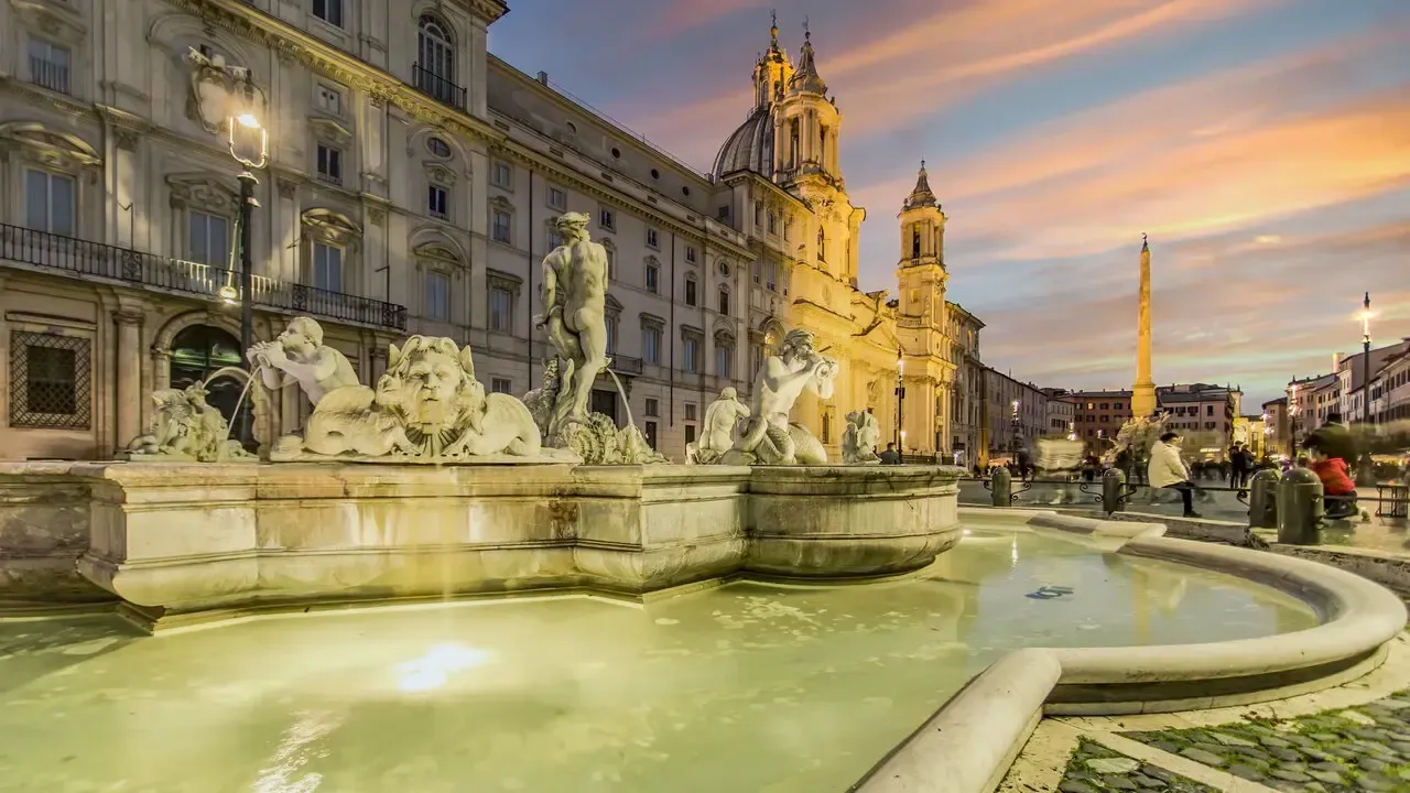 Fountain of Four Rivers in Piazza Navona, Rome, Italy, with statues, architecture, and a sunset sky.