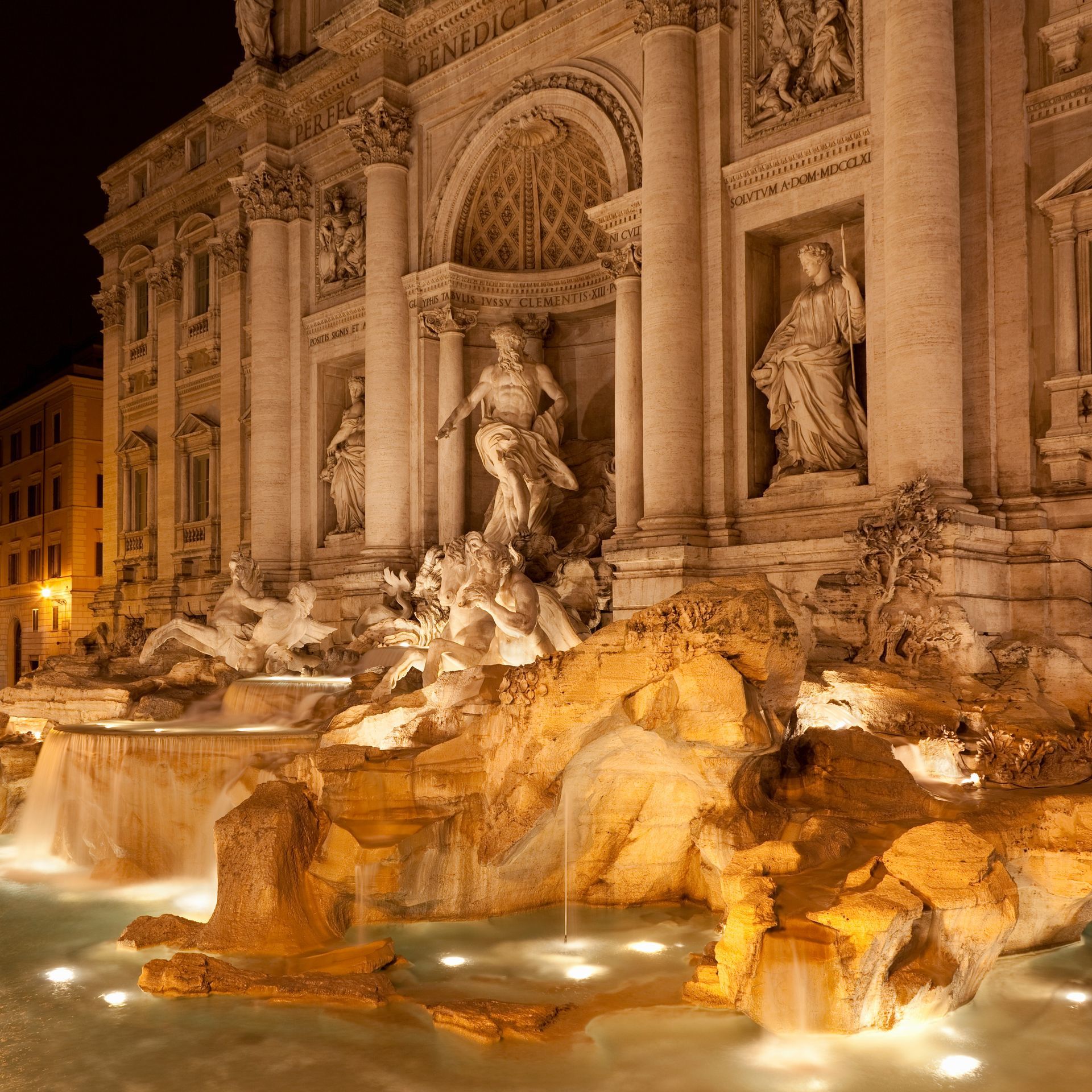 Trevi Fountain at night, Rome, illuminated. Baroque architecture with cascading water and sculptures.