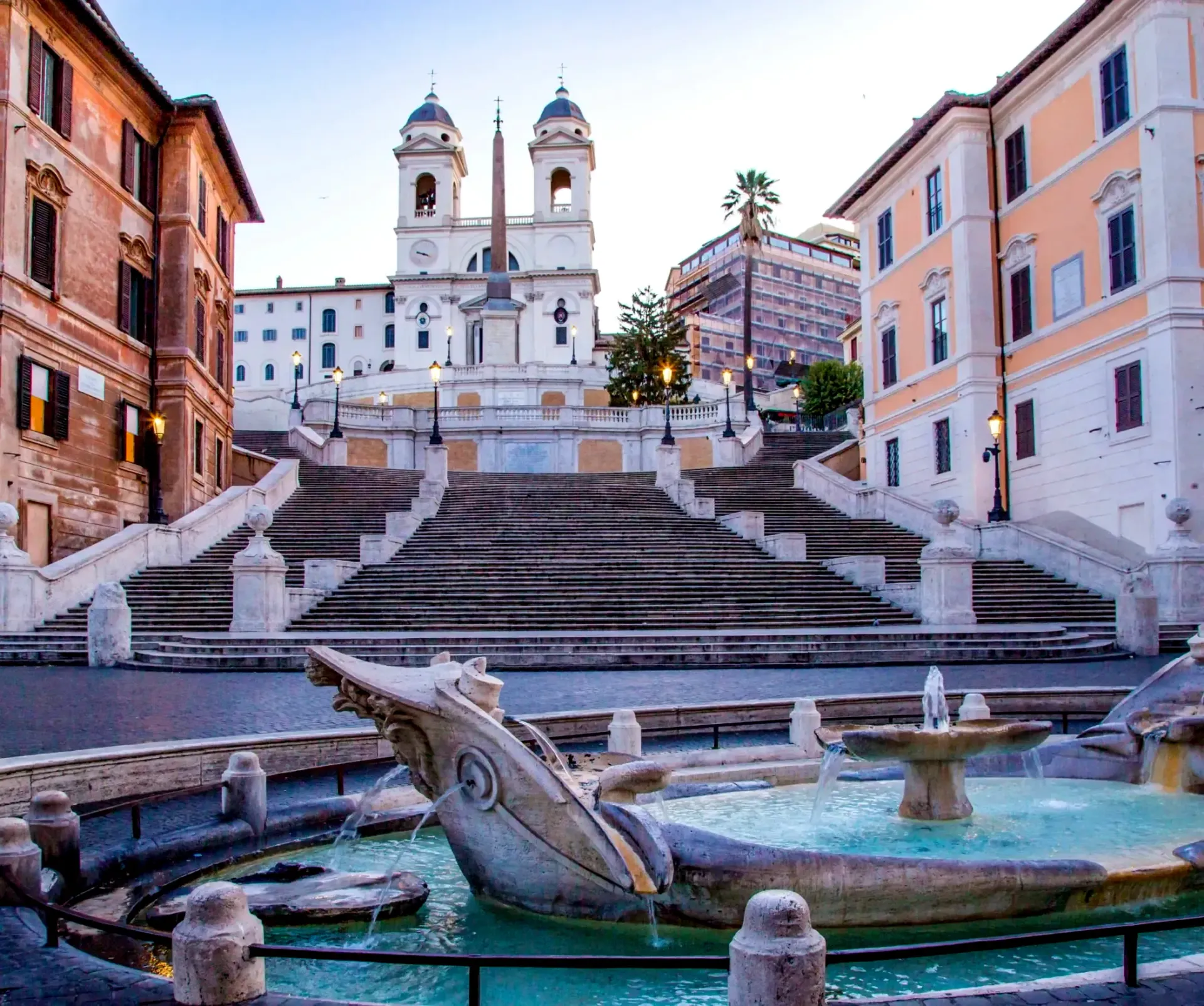 Spanish Steps and a fountain in Rome. Buildings flank a wide staircase; the fountain features a sculpted boat.