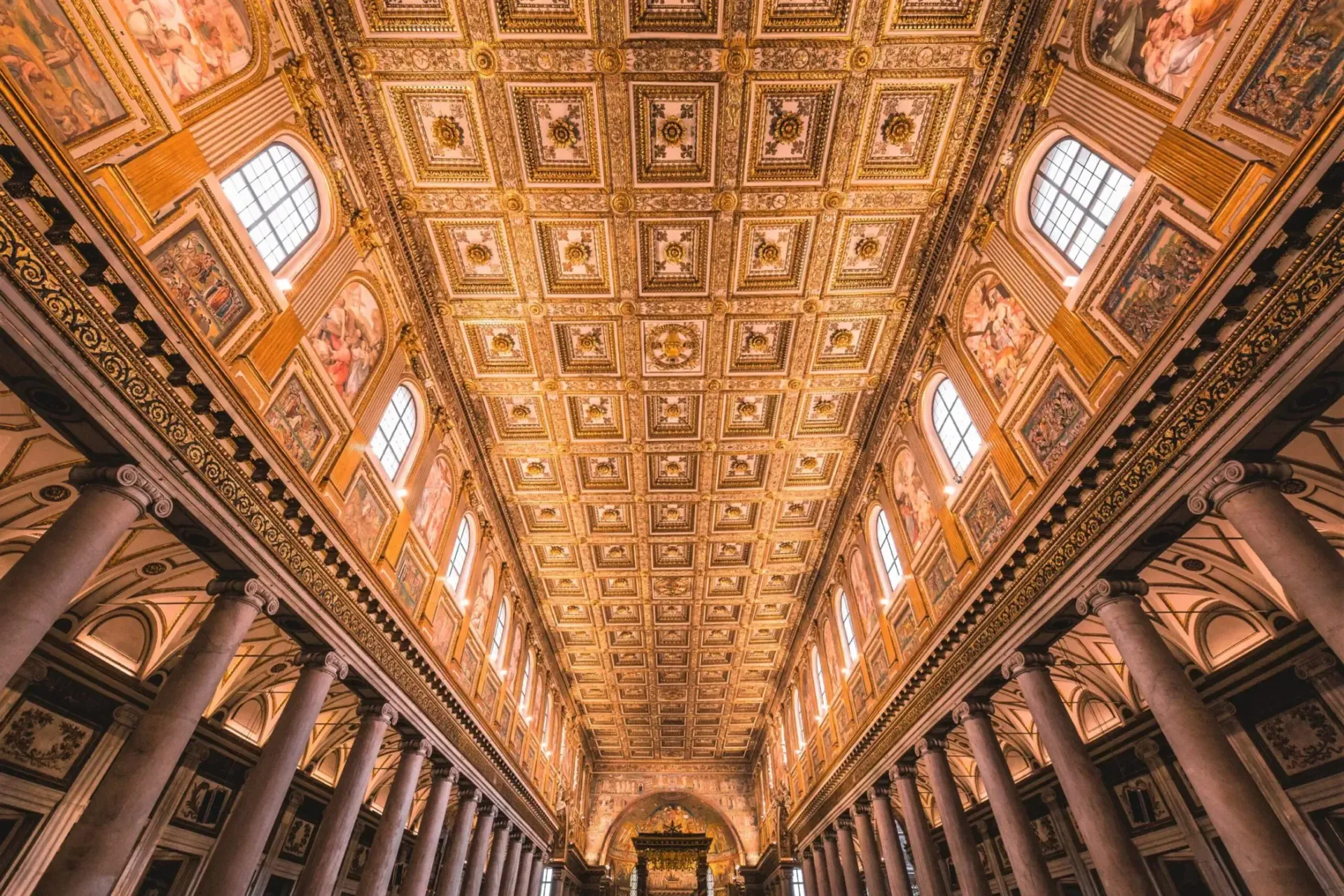 St. Peter's Basilica, Rome, with tourists in the square under a cloudy sky.