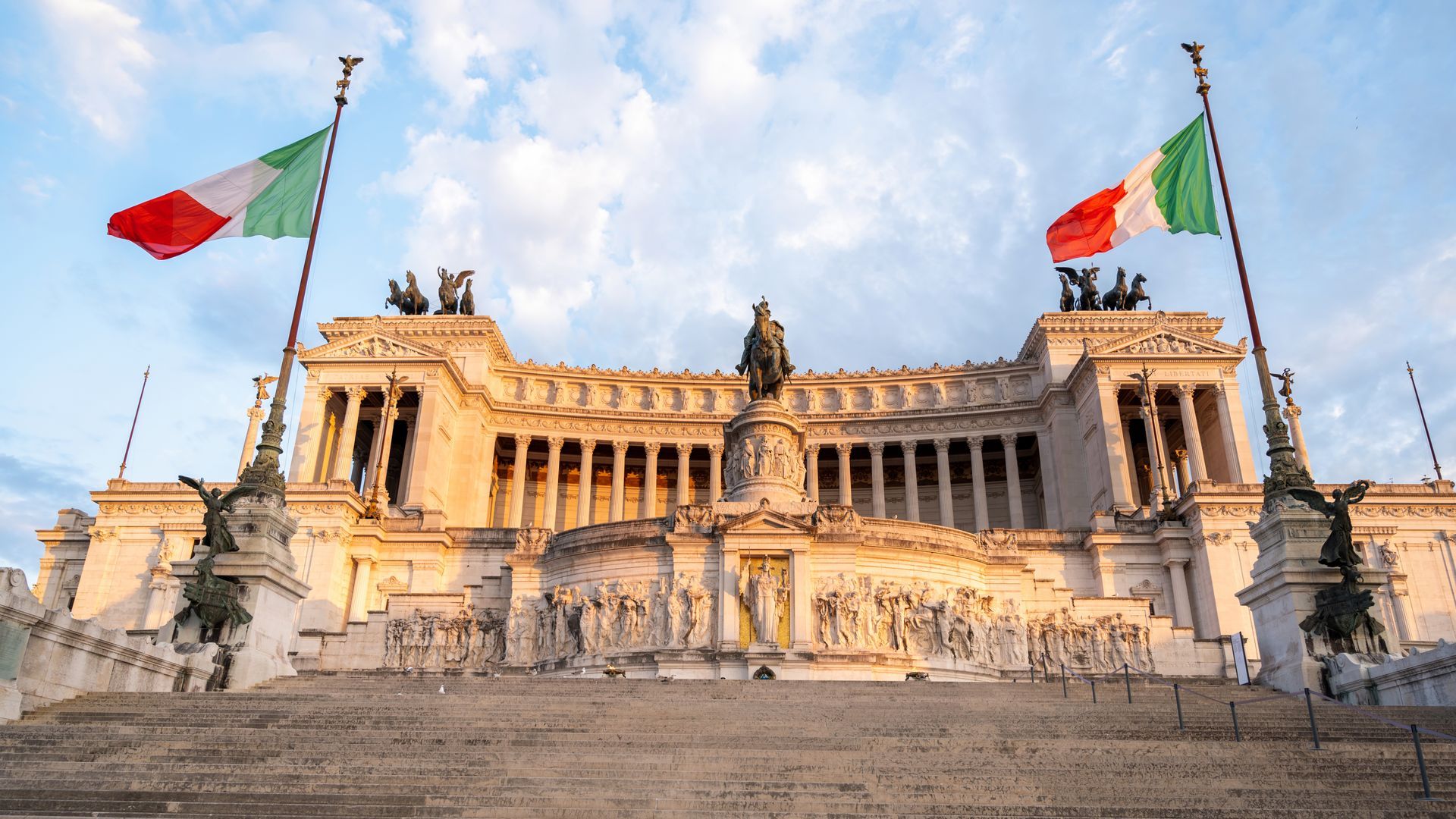 National Monument of Victor Emmanuel II, Rome, with Italian flags. White marble building.