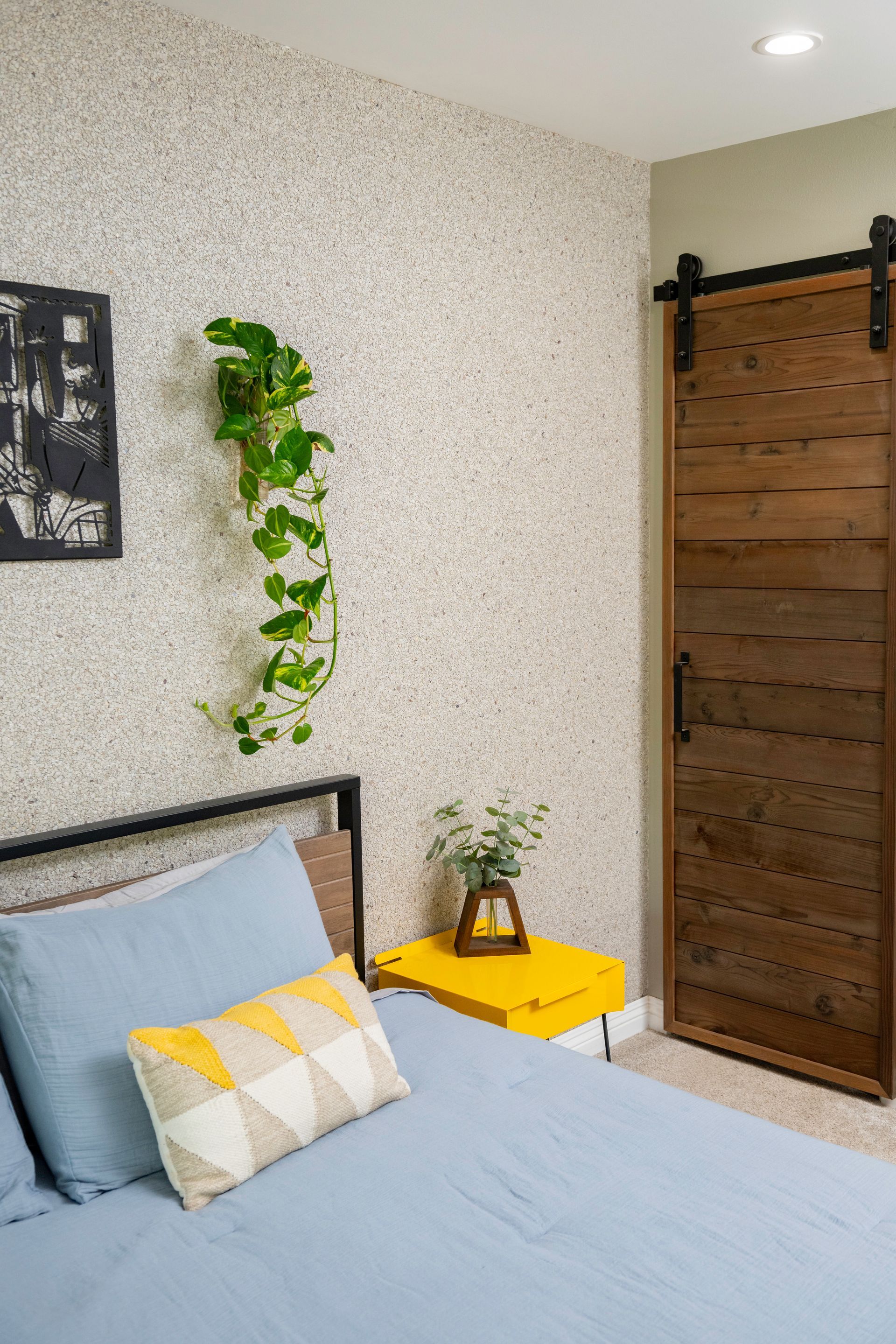 A bedroom with a bed , nightstand , and sliding barn door.