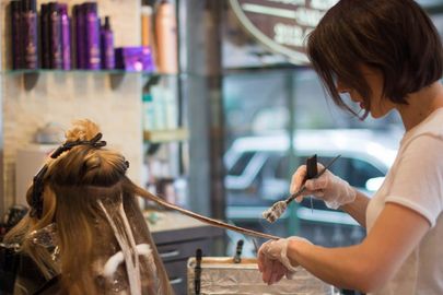 A woman is getting her hair dyed in a salon.