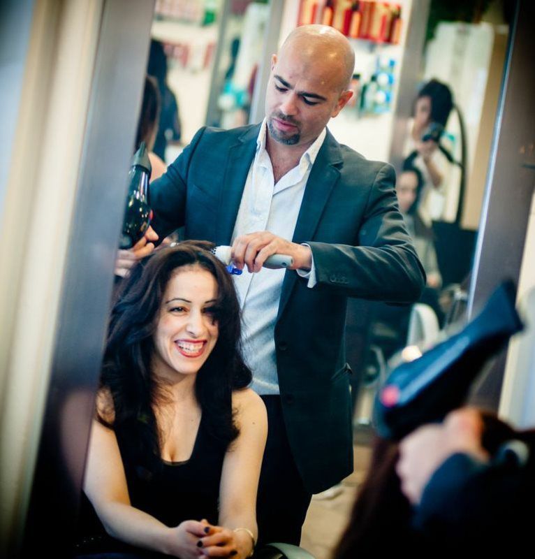 A man in a suit is blow drying a woman 's hair